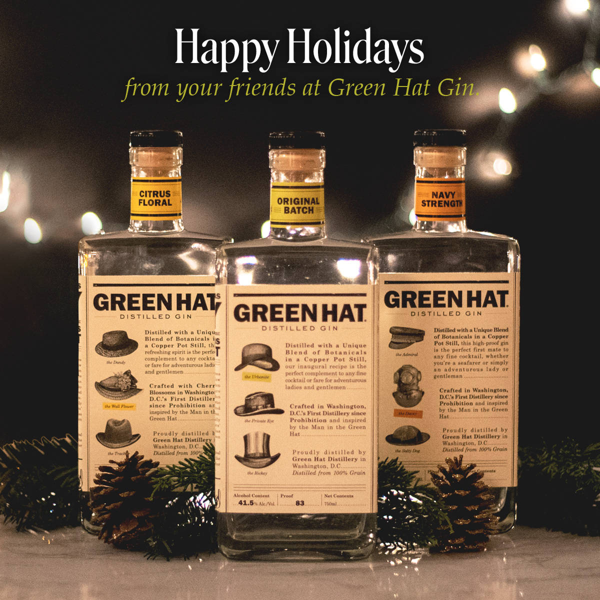 Gin 桌布 壁紙 — 三瓶標有 Citrus Floral Original Batch 和 Navy Strength 的 Green Hat Gin 酒瓶放在白色表面上，旁邊有松果和花環，背景是溫暖的散景燈光。