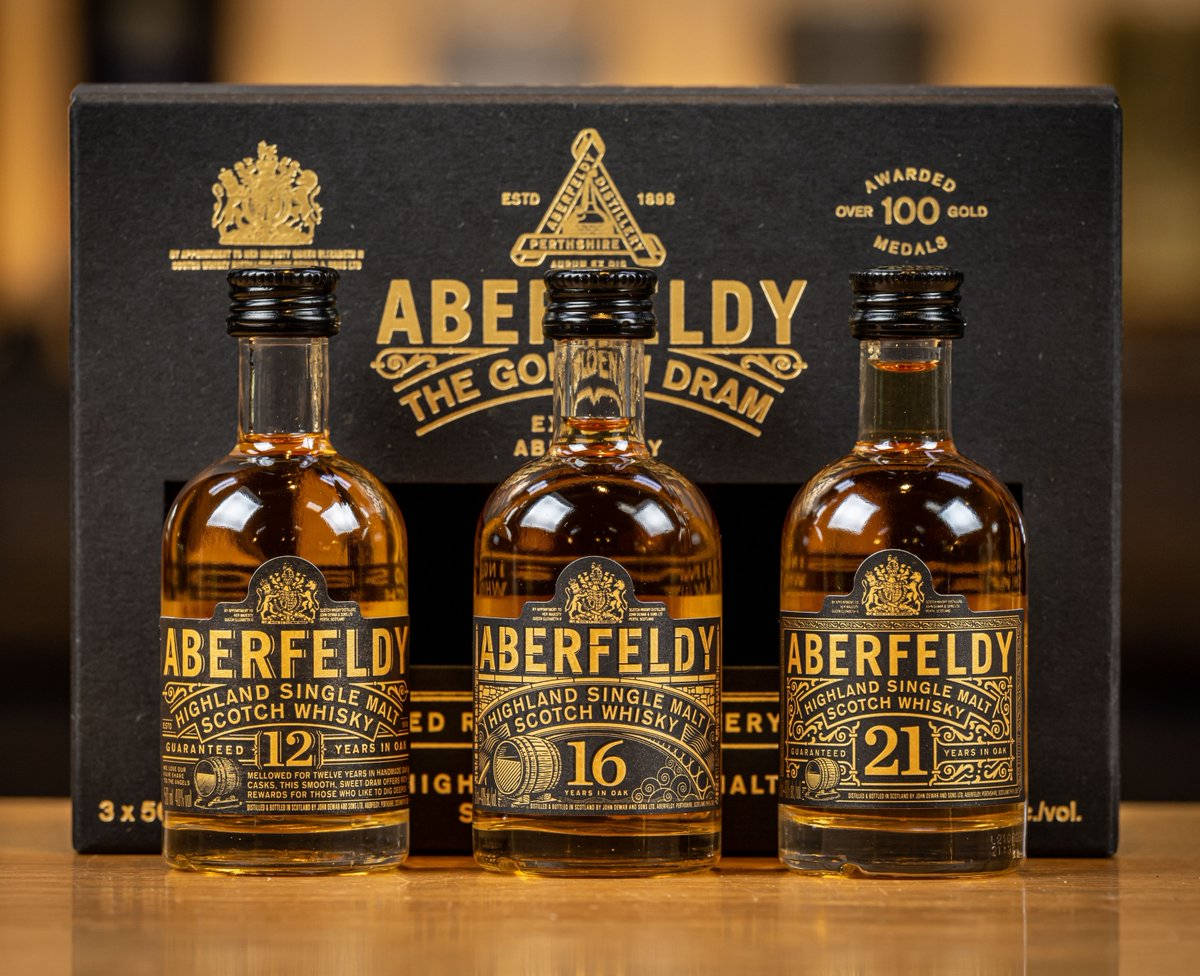 飲料 桌布 壁紙 — 三瓶琥珀色的Aberfeldy威士忌，年份分別為12年、16年和21年，展示在她們的黑色豪華盒子前，放在木質表面上。