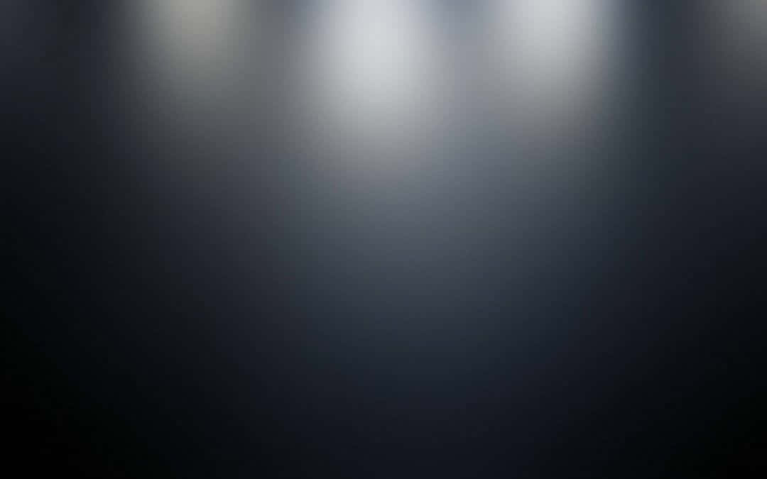 Black Gradient 桌布 壁紙 — 三盞明亮的聚光燈照亮黑暗的舞台，營造出光影的戲劇性漸變。