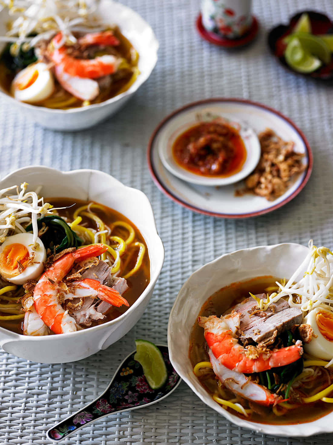 Noodles 桌布 壁紙 — 三碗濃郁的麵湯，配上蝦、水煮蛋、豆芽和青菜，放在編織墊上。