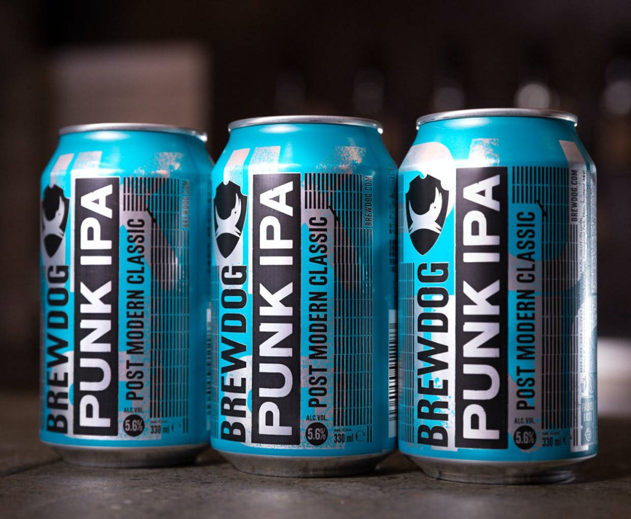 Drink 桌布 壁紙 — 三罐亮藍色的BrewDog Punk IPA啤酒罐排列在深色木質表面上，景深較淺。