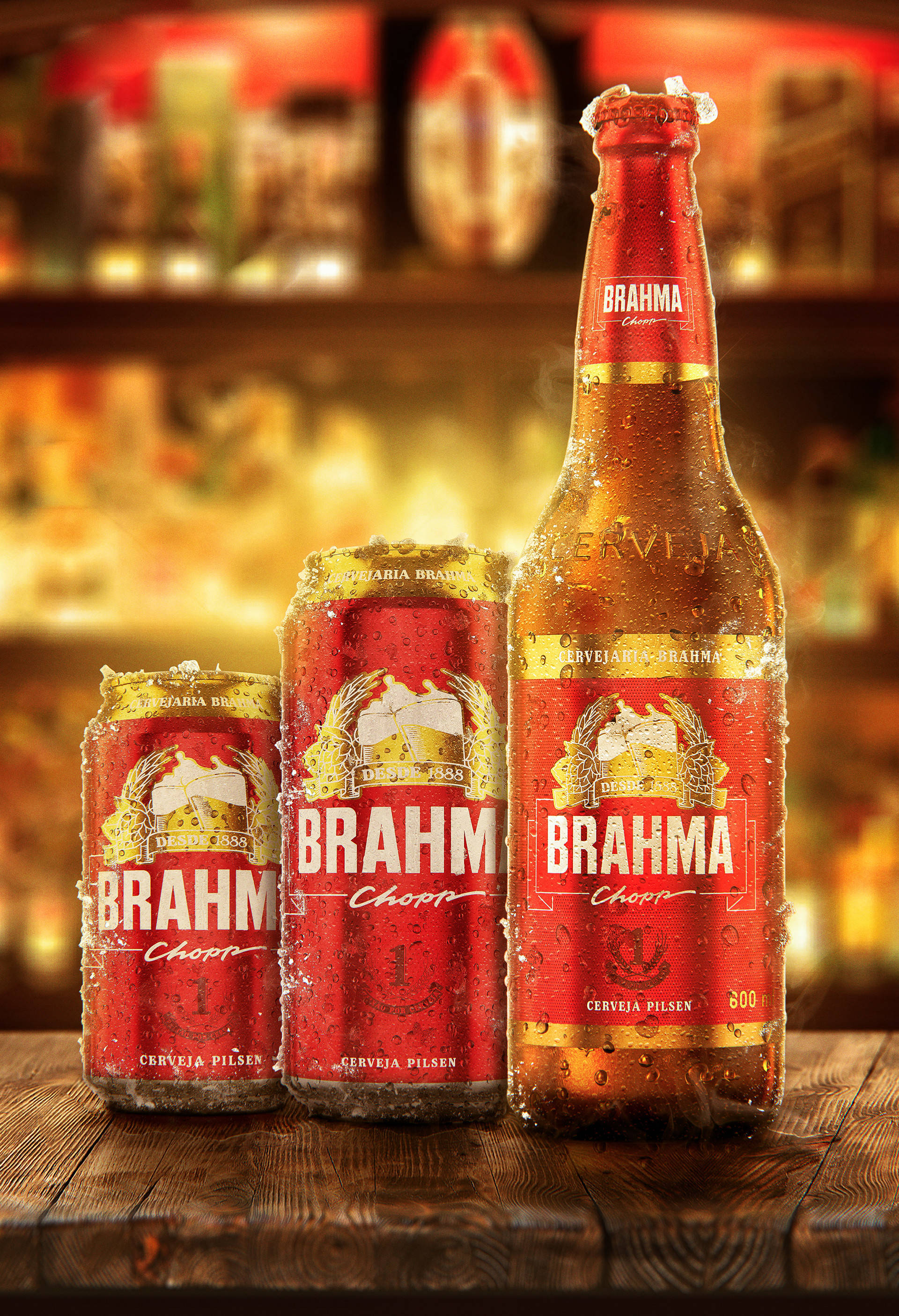 Drink 桌布 壁紙 — 三罐冰涼的 Brahma 啤酒罐和一瓶啤酒在質樸的木吧台上閃爍著冷凝水珠，背景是溫暖燈光下模糊的酒吧。
