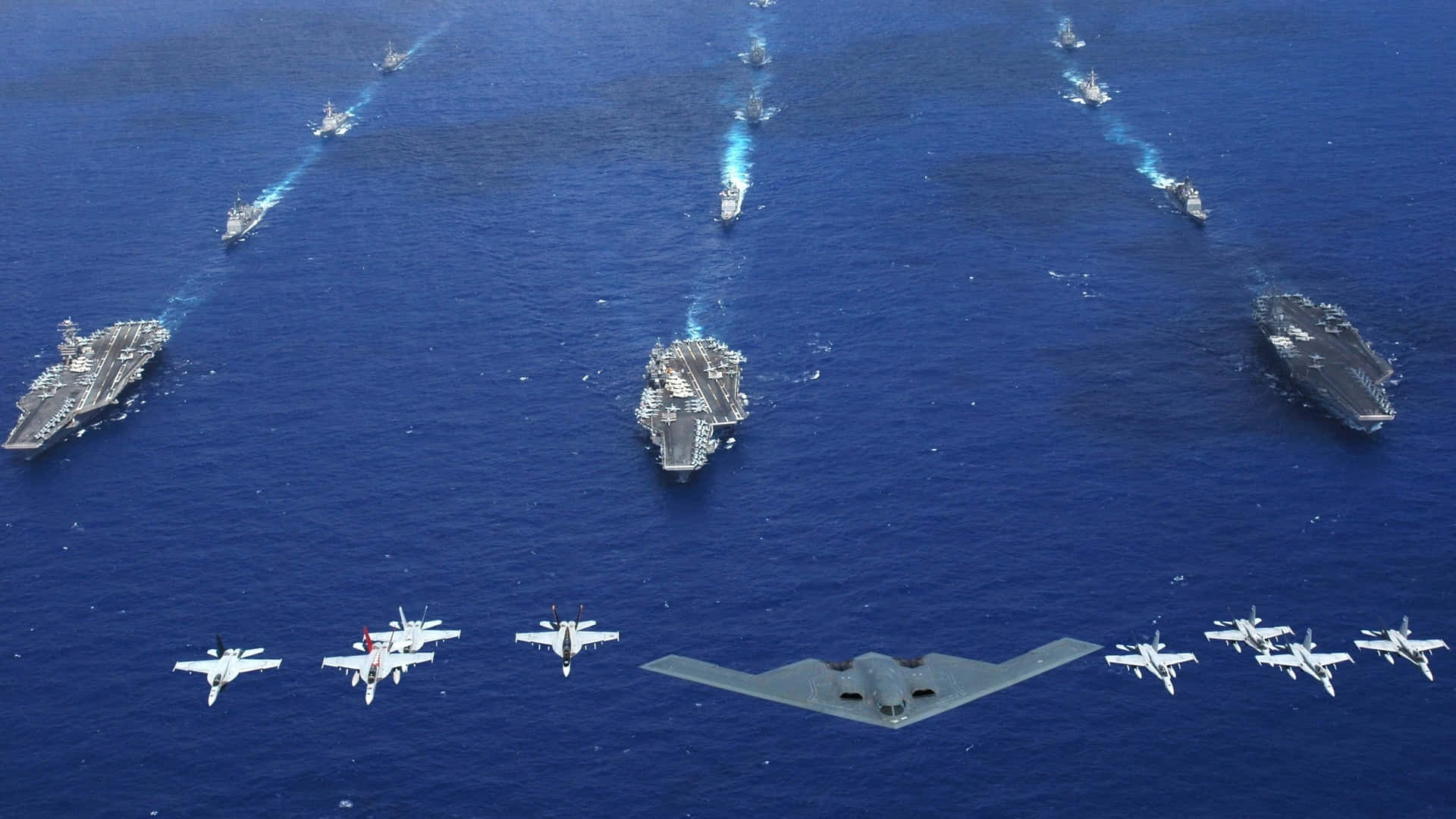 Navy 桌布 壁紙 — 三艘航空母艦及戰鬥機在深藍色海洋上空編隊飛行的鳥瞰圖。