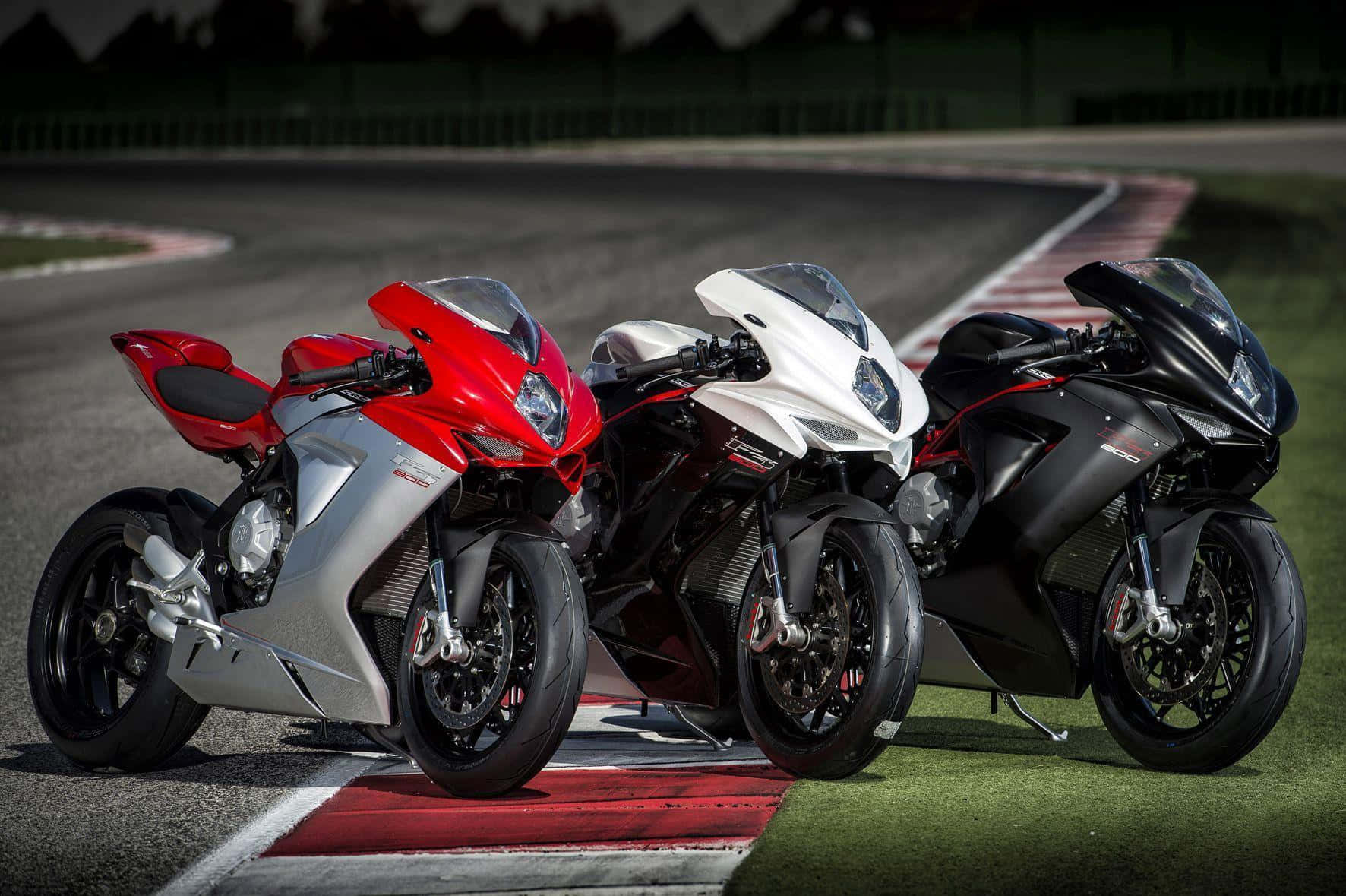 Superbike 桌布 壁紙 — 三輛紅色、白色和黑色的運動機車並排停放在賽道邊緣。