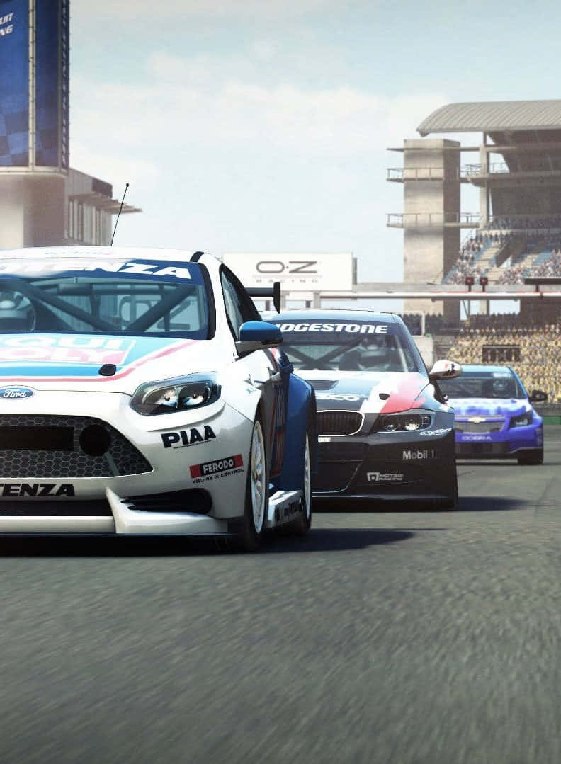 iPhone X Grid Autosport 桌布 壁紙 — 三輛賽車在陽光普照的瀝青賽道上激烈競爭，背景有看台和贊助商橫幅。