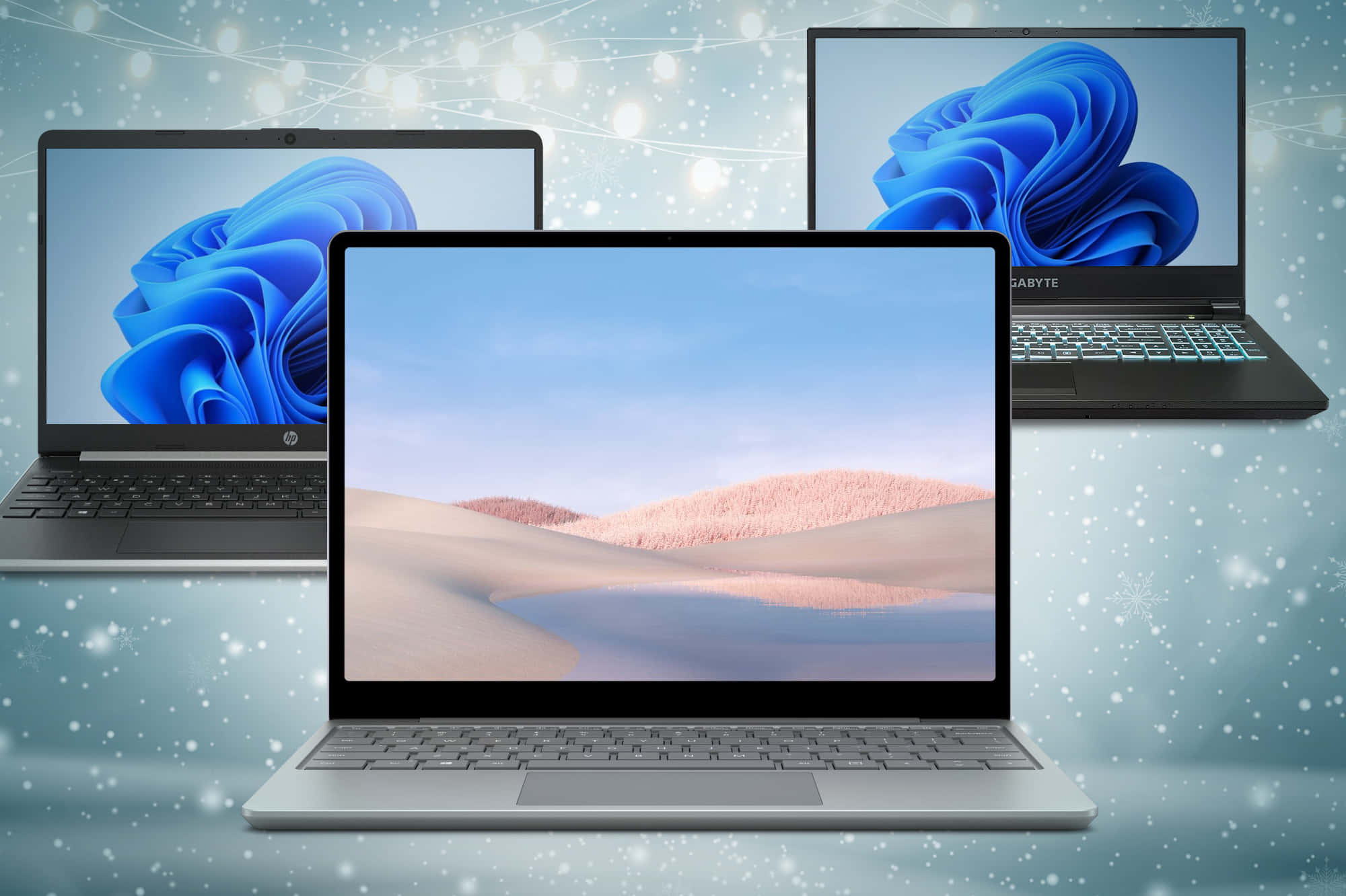 筆電 桌布 壁紙 — 三部筆記型電腦在雪景節日背景中展示帶有燈串的Windows 11桌布。