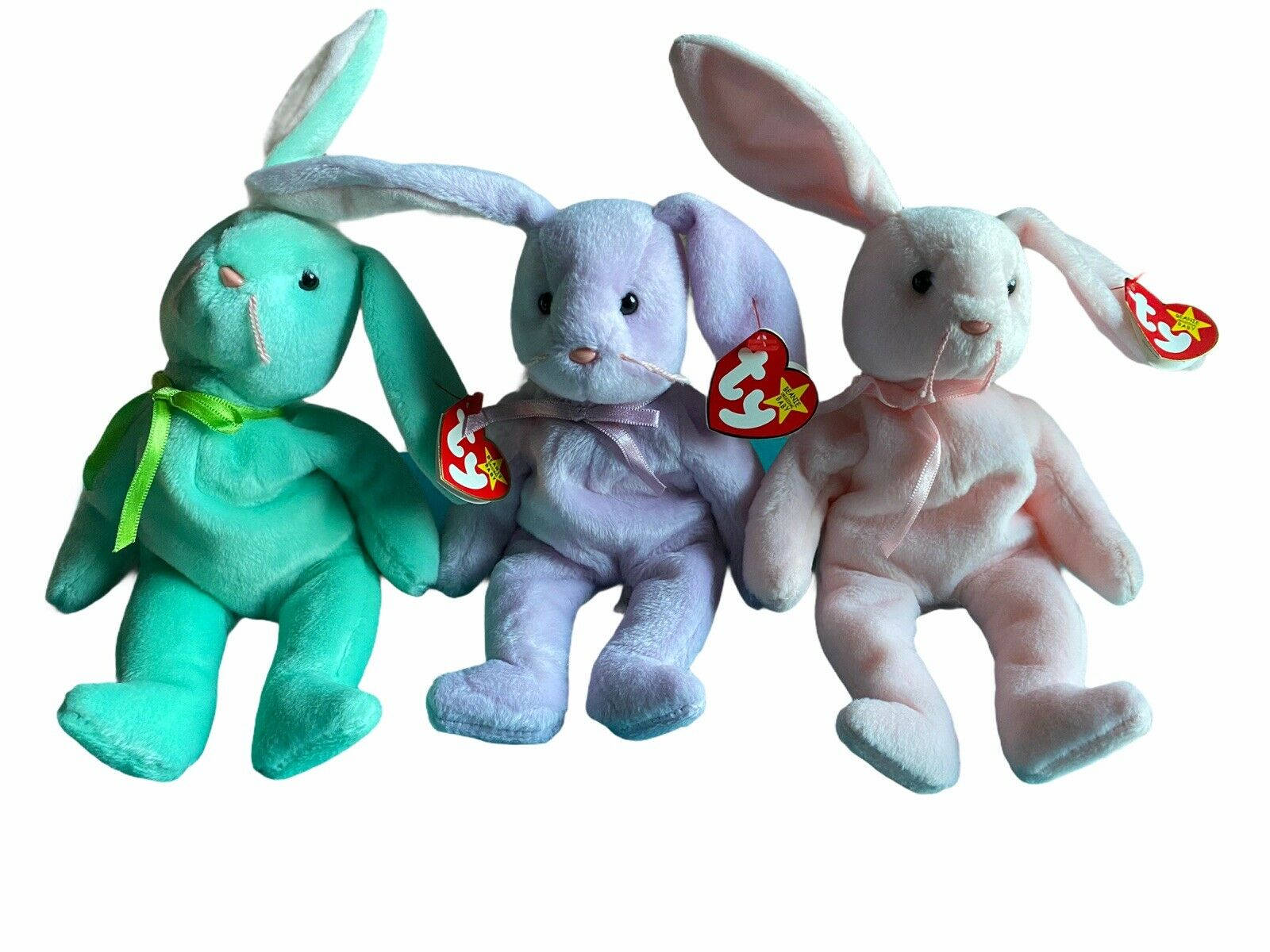 Beanie 桌布 壁紙 — 三隻 Ty Beanie Babies 兔子，顏色分別為青綠色、薰衣草色和粉紅色，並排坐在純白色背景前。