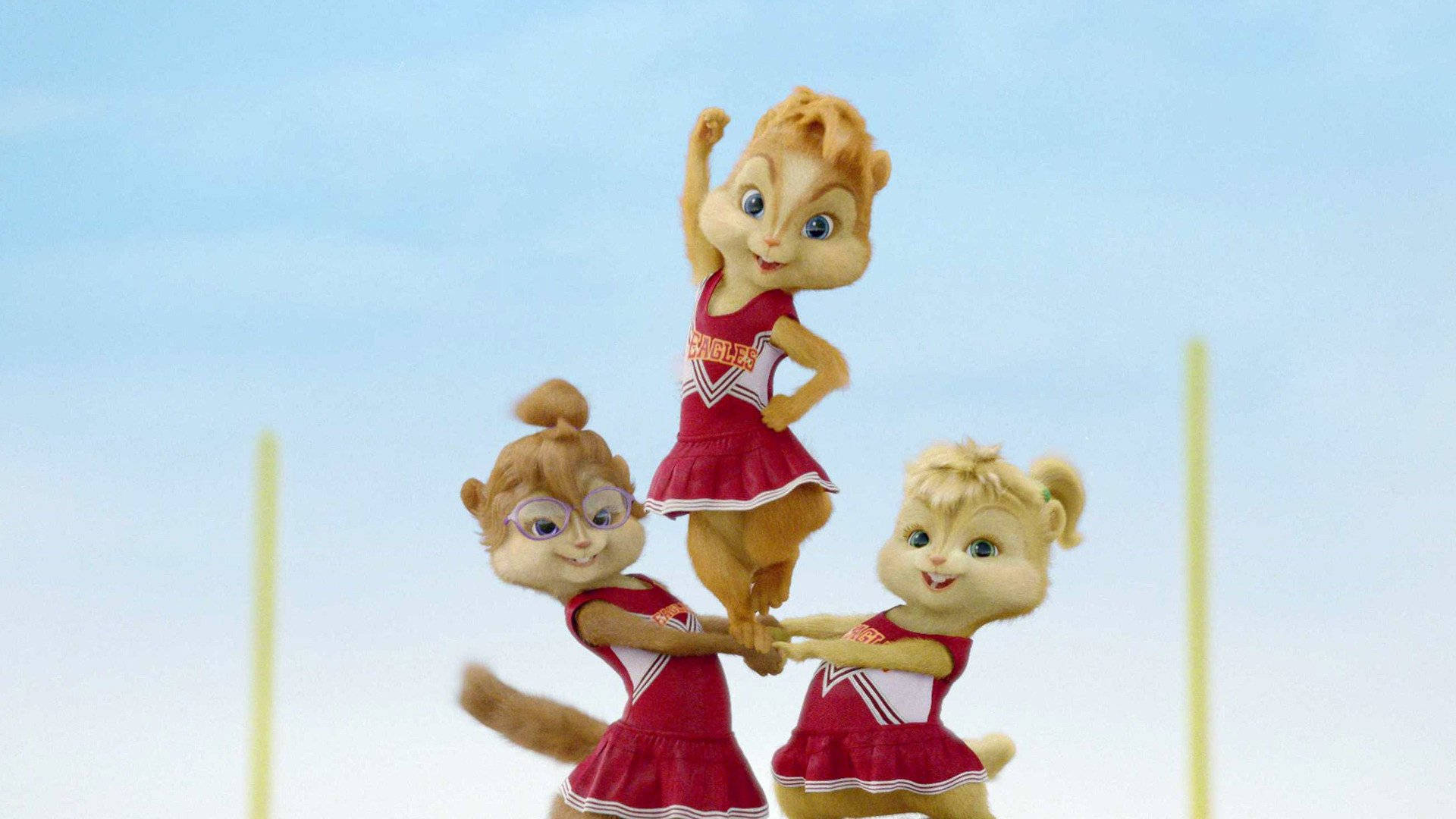 Chipmunks 桌布 壁紙 — 三隻動畫花栗鼠穿著紅色啦啦隊制服，在晴朗的藍天下擺出歡樂的金字塔姿勢。