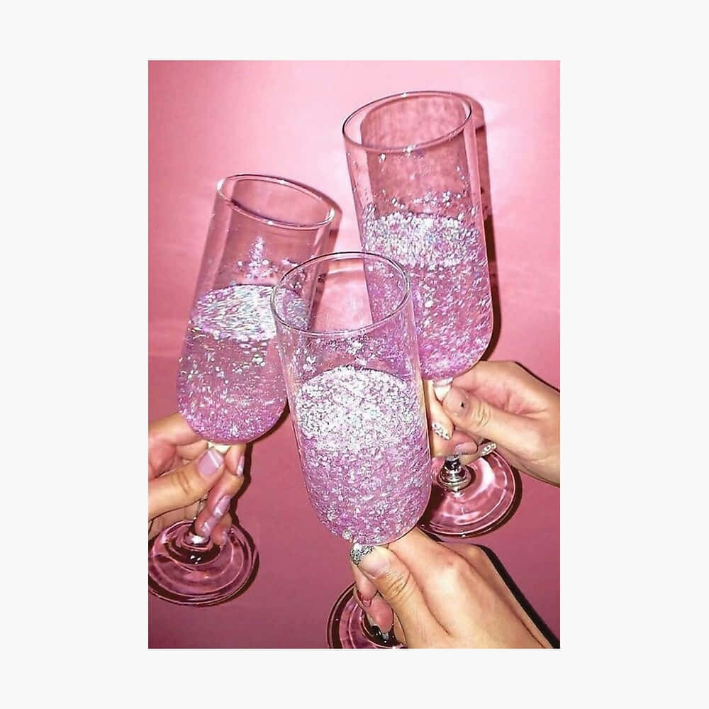 drinks 桌布 壁紙 — 三隻手在柔和的粉紅色背景下，碰杯閃爍的粉紅色香檳杯，杯中裝滿閃閃發光的液體。