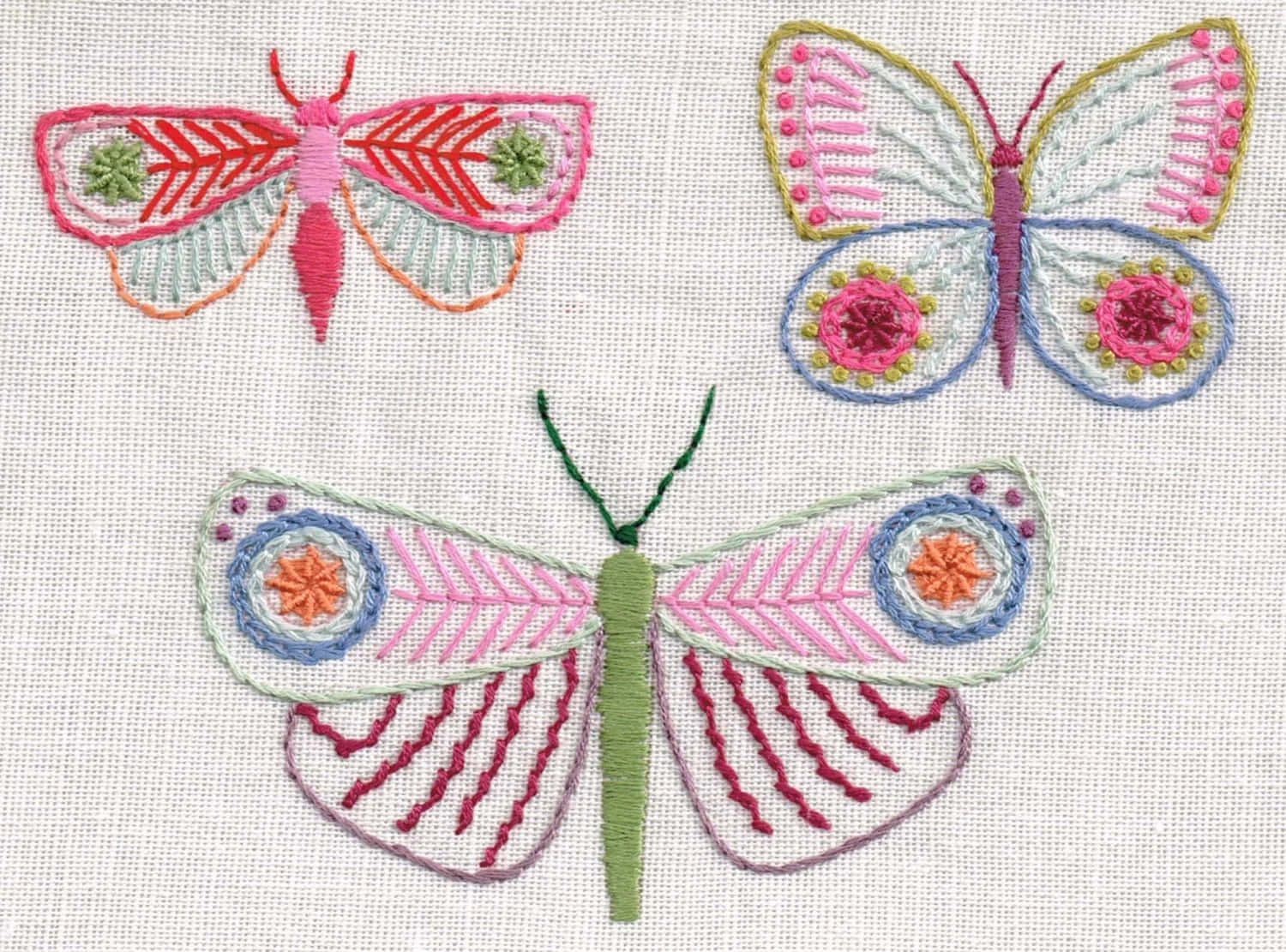 Butterfly Stitch 桌布 壁紙 — 三隻色彩繽紛的刺繡蝴蝶，帶有精緻圖案繡在輕柔布料上。