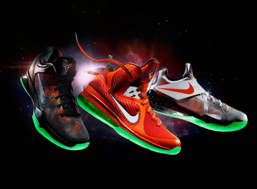 Nike Shoes 桌布 壁紙 — 三雙充滿活力的籃球鞋漂浮在宇宙星空中，帶有發光的綠色鞋底和火熱的橙色點綴。