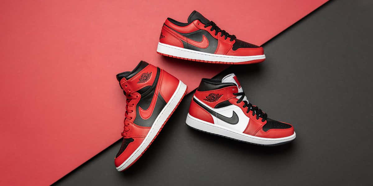 Air Jordan 1 桌布 壁紙 — 三雙紅、黑、白色的 Air Jordan 1 運動鞋以對角線排列在紅黑分割的背景上。