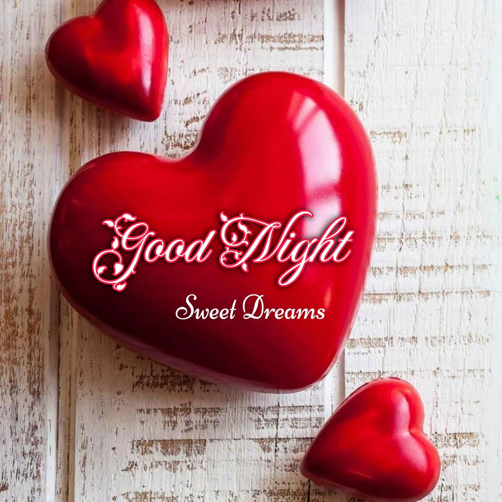 Red Hearts 桌布 壁紙 — 三顆光滑的紅色心形放在風化的白色木頭上，上面以優雅草書寫著「Good Night Sweet Dreams」。