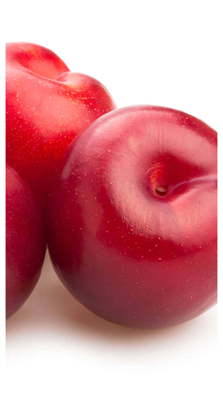 Red Plum 桌布 壁紙 — 三顆帶有露珠的光澤紅李，在純白背景上以緊密特寫呈現。