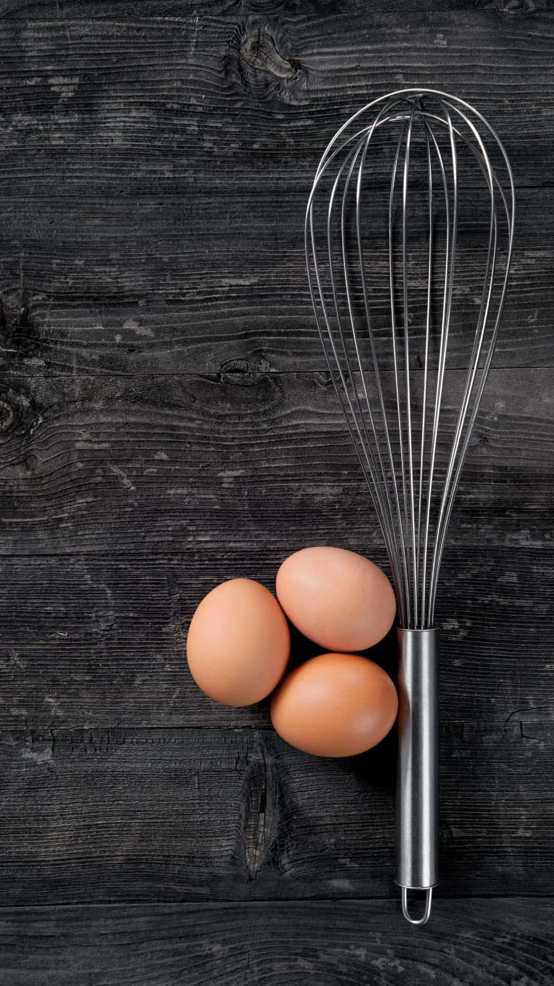 Egg 桌布 壁紙 — 三顆棕色雞蛋和一個金屬打蛋器放在深色鄉村風木質表面上。