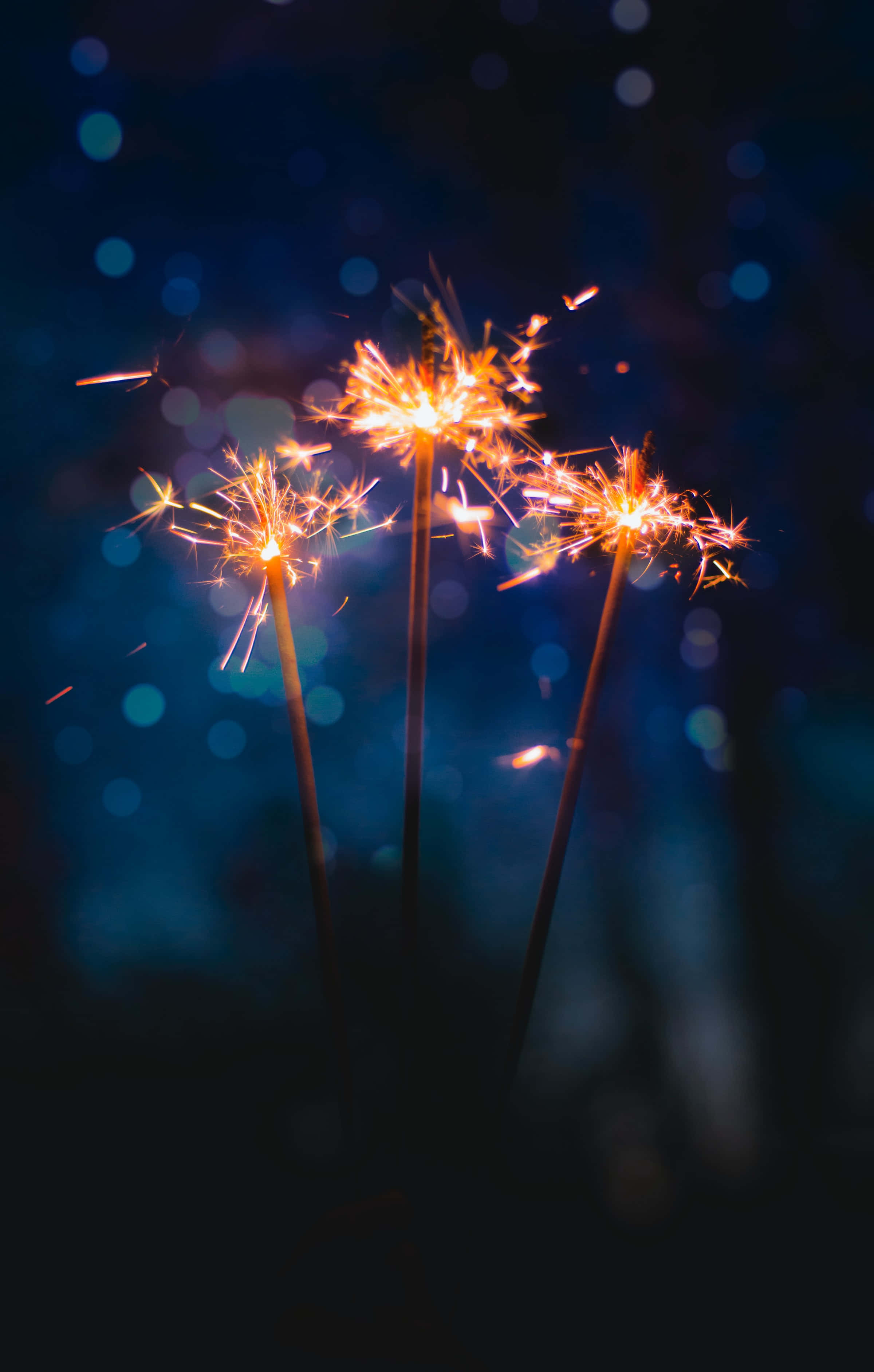 sparklers 桌布 壁紙 — 三顆閃爍的煙火在深藍色散景夜空綻放出金色光芒。