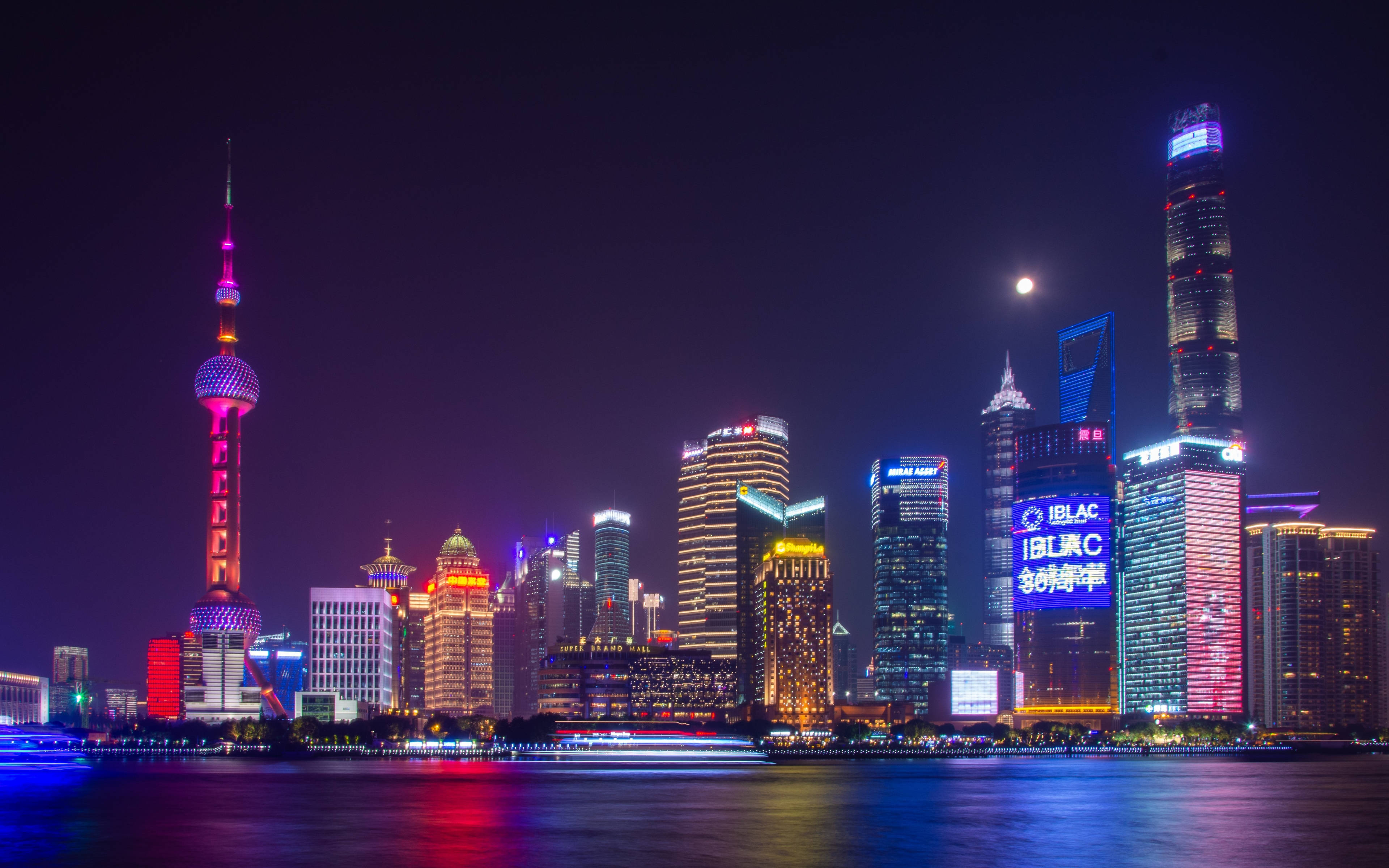 漂亮的桌面 桌布 壁紙 — 上海令人目眩神迷的夜景天際線，閃爍的摩天大樓和標誌性的東方明珠塔在月光下的黃浦江上倒映。
