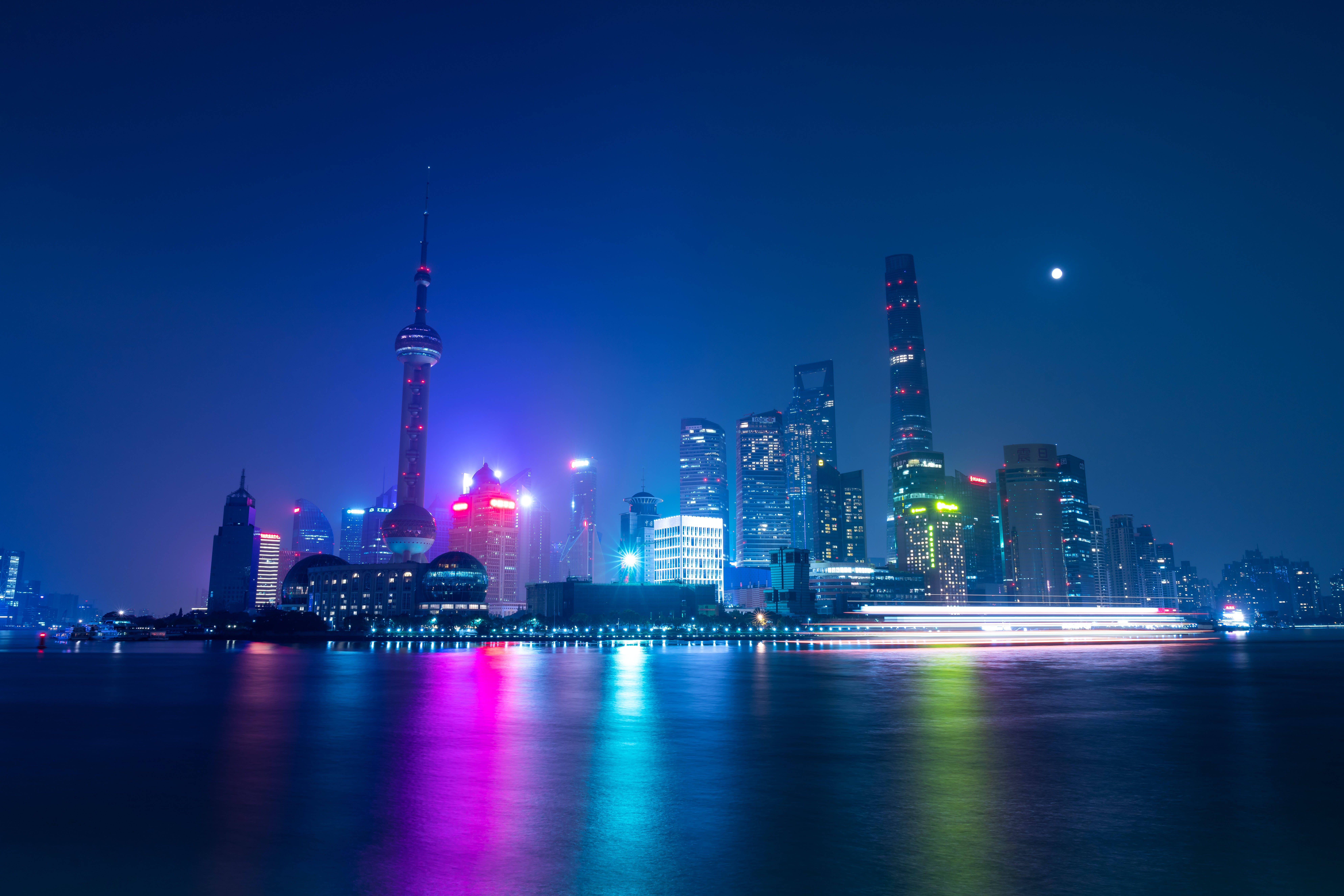 霓虹城市動態圖 桌布 壁紙 — 上海充滿活力的夜景天際線，霓虹燈閃爍的摩天大樓在月光下的黃浦江上倒映。