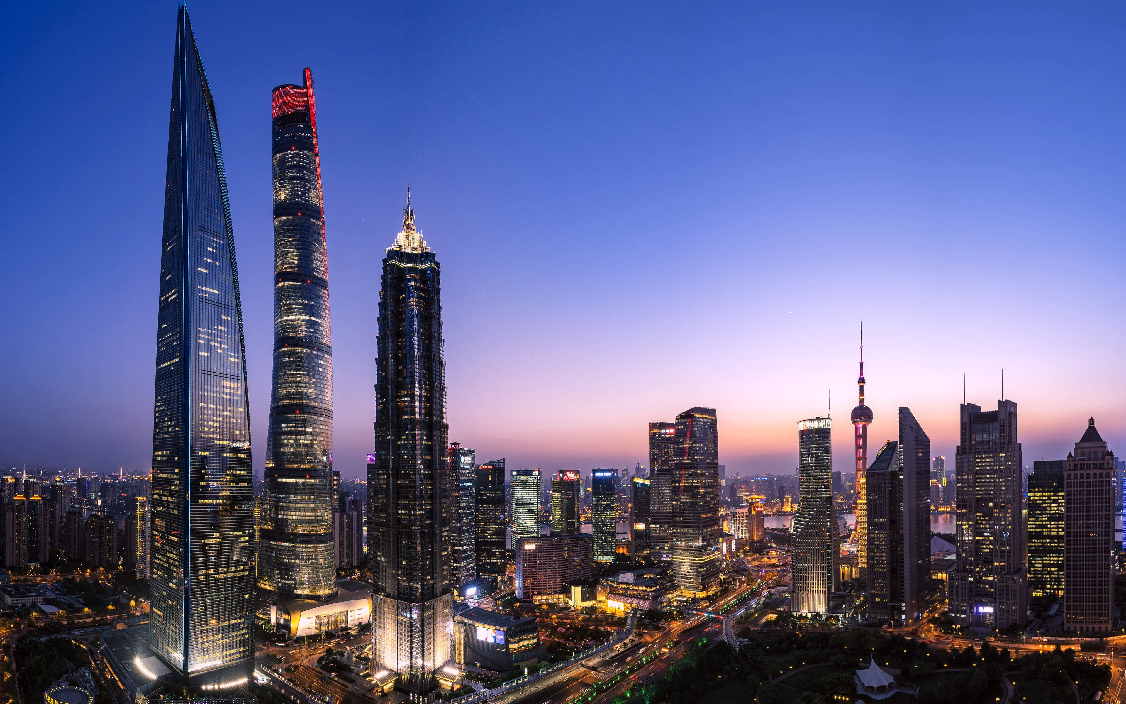 Shanghai 桌布 壁紙 — 上海天際線的壯麗黃昏景色，摩天大樓在漸變紫色和藍色天空的映襯下閃爍著燈光。