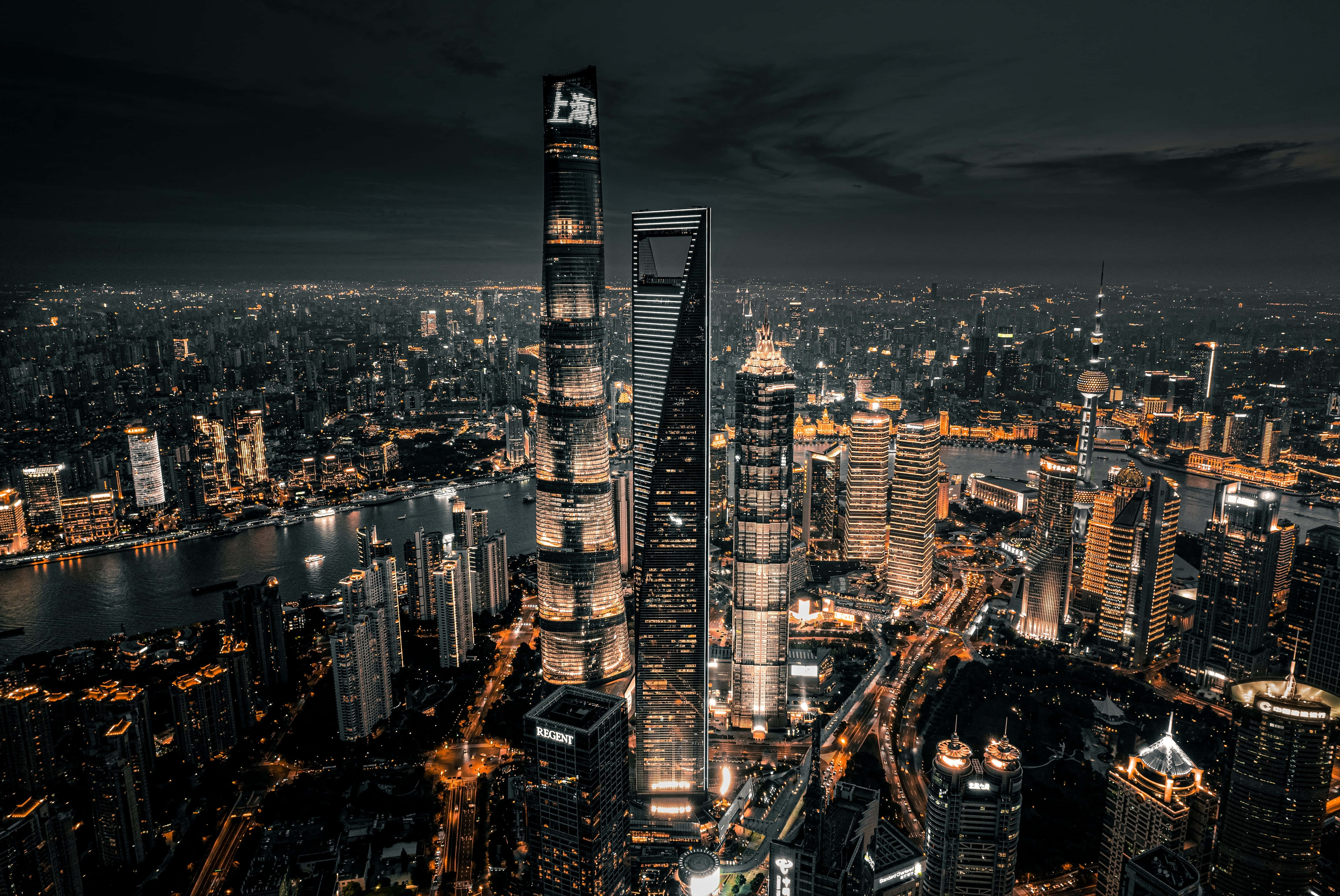 standard 桌布 壁紙 — 上海璀璨摩天大樓與河流的夜間航拍，城市燈光在黑暗天空中閃耀。