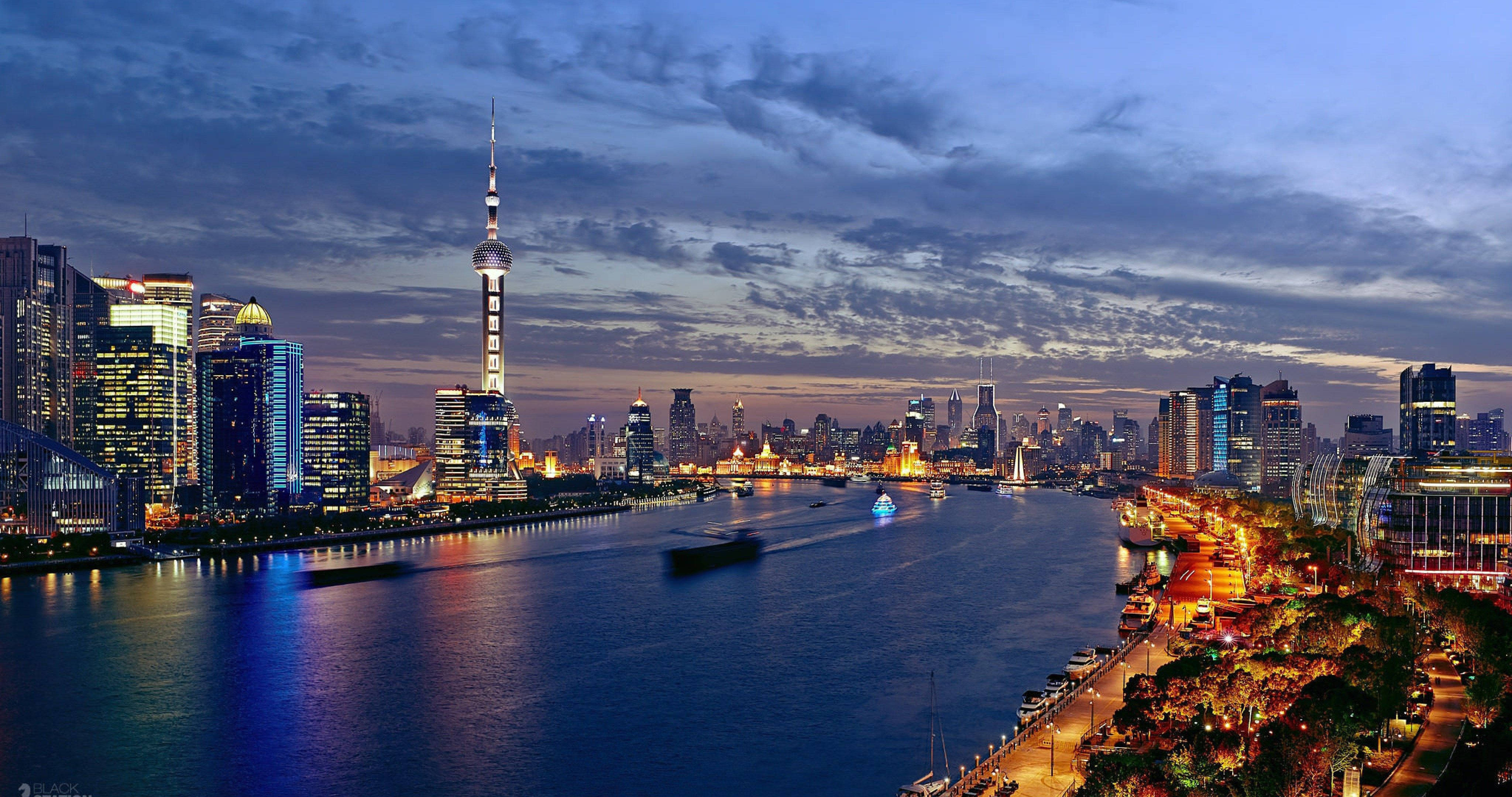 Shanghai 桌布 壁紙 — 上海黃昏時分璀璨天際線的全景，黃浦江倒映著城市燈光與往來的船隻。