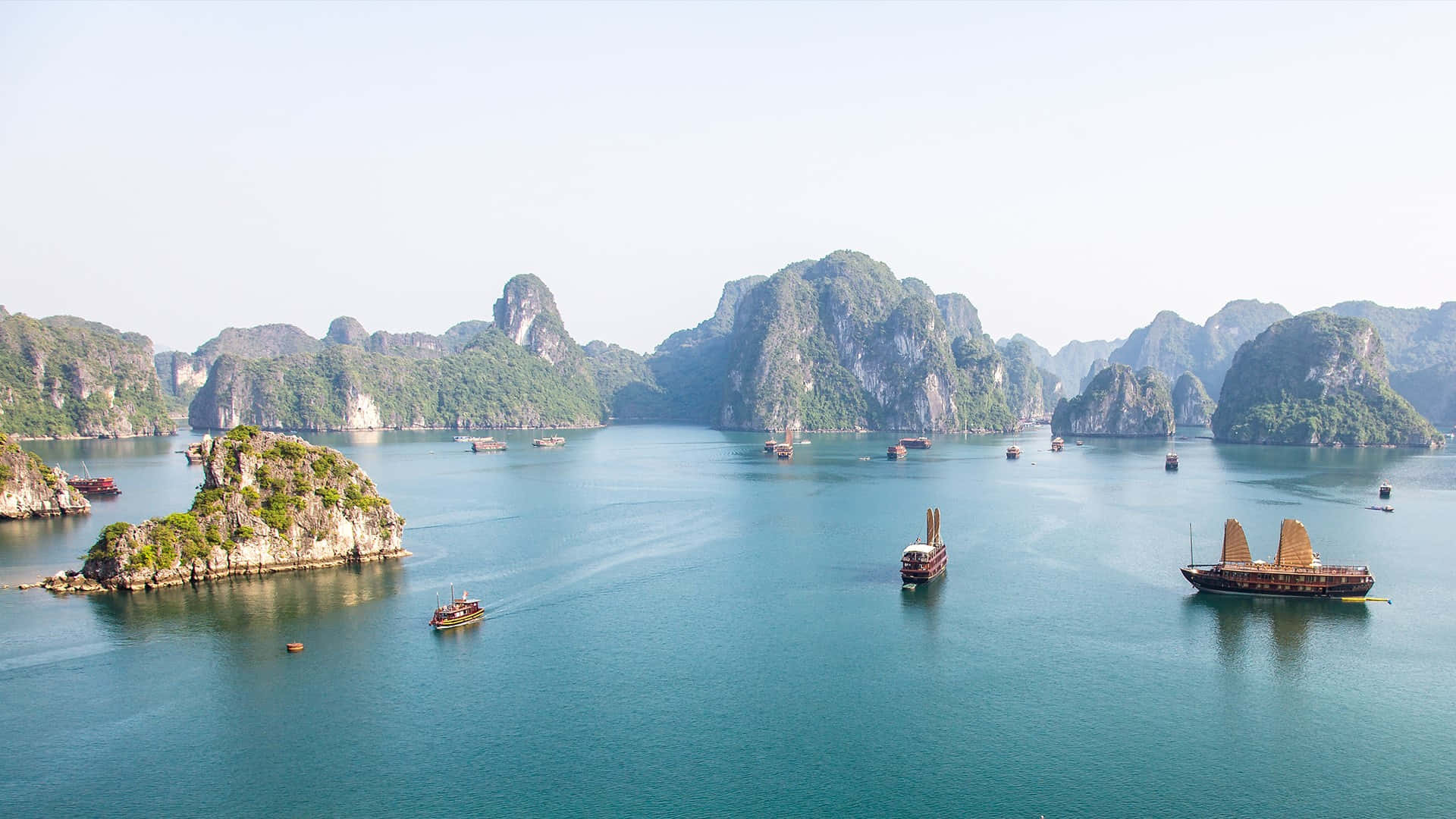 Vietnam 桌布 壁紙 — 下龍灣的鳥瞰圖，石灰岩喀斯特地貌從碧綠的海水中升起，點綴著傳統的帆船。
