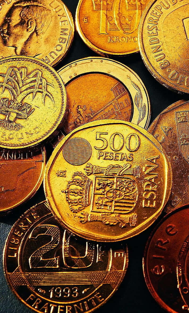 金錢 桌布 壁紙 — 不同國家的金色和銅色硬幣散落在深色表面上的特寫。