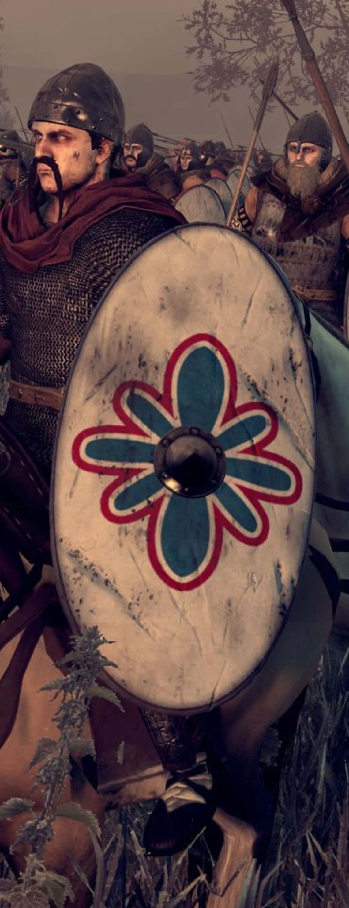 shield 桌布 壁紙 — 中世紀戰士在戰場中手持一個帶有紅藍花卉圖案的圓盾的特寫。
