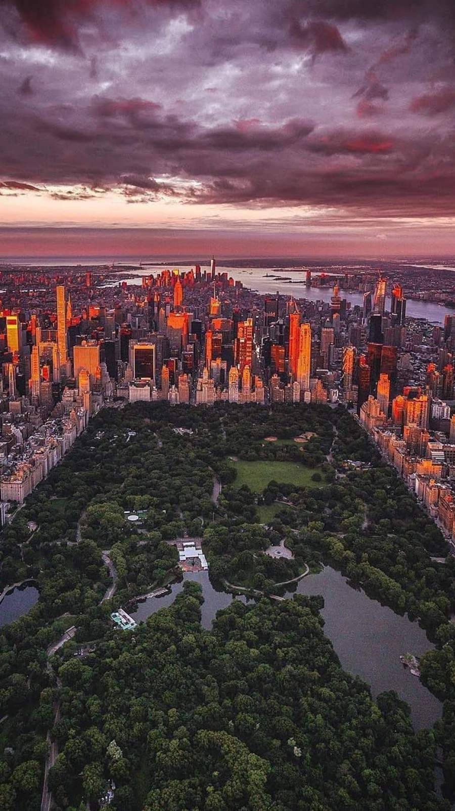 New York HD 桌布 壁紙 — 中央公園的鳥瞰圖，被發光的摩天大樓環繞，在戲劇性的暮色天空下。