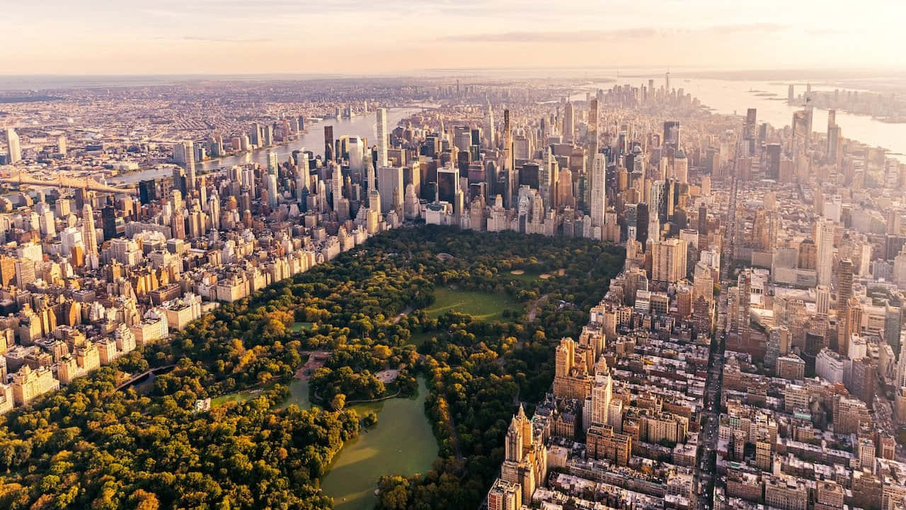 720p Ny City 桌布 壁紙 — 中央公園被紐約市摩天大樓環繞，沐浴在金色夕陽下的鳥瞰圖。