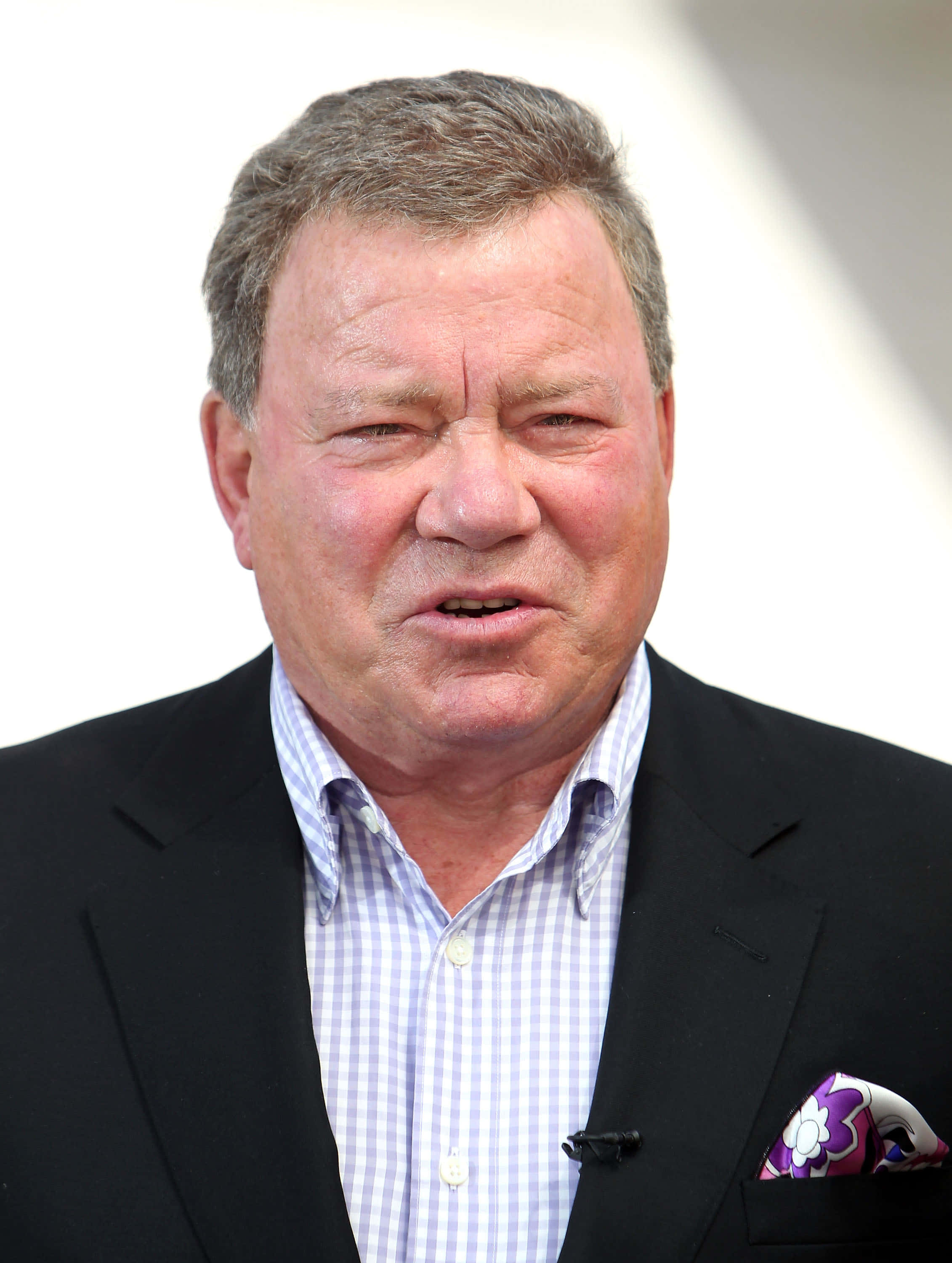william shatner 桌布 壁紙 — 中年男子身穿黑色西裝和格紋襯衫，搭配色彩繽紛的口袋方巾的 close-up 肖像。