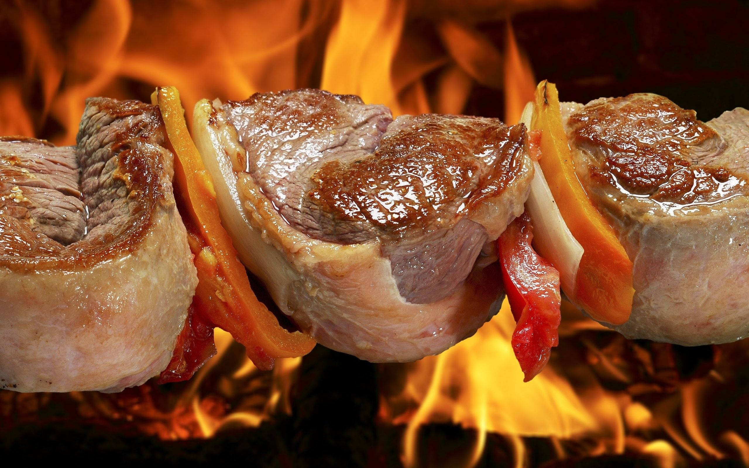 meat 桌布 壁紙 — 串上的肉和辣椒在熊熊烈火和熾熱餘燼中烤得滋滋作響。