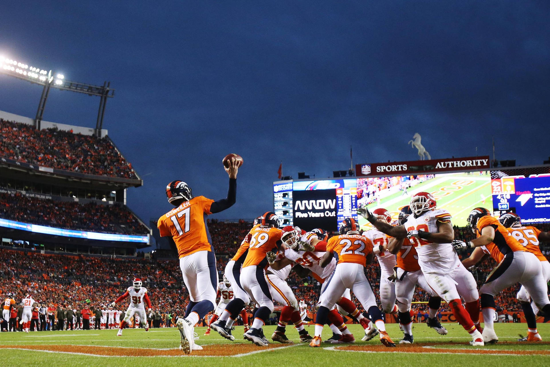 丹佛野馬隊四分衛在夜間足球比賽中傳球。 — NFL GIF 壁紙