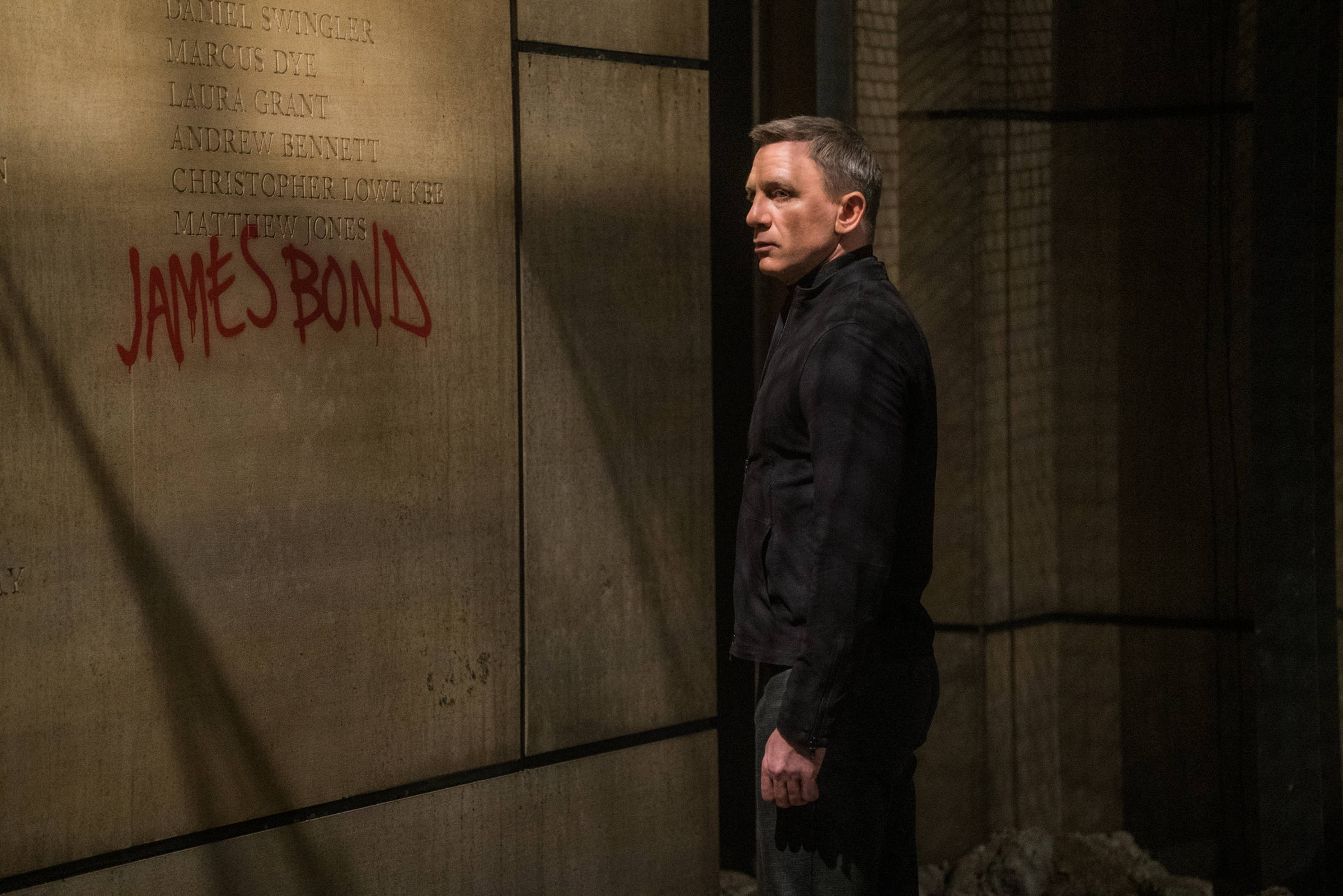 Daniel Craig 桌布 壁紙 — 丹尼爾·克雷格飾演詹姆士·龐德，站在陰暗的城市小巷中，旁邊的牆上以紅色噴漆噴上他的名字。