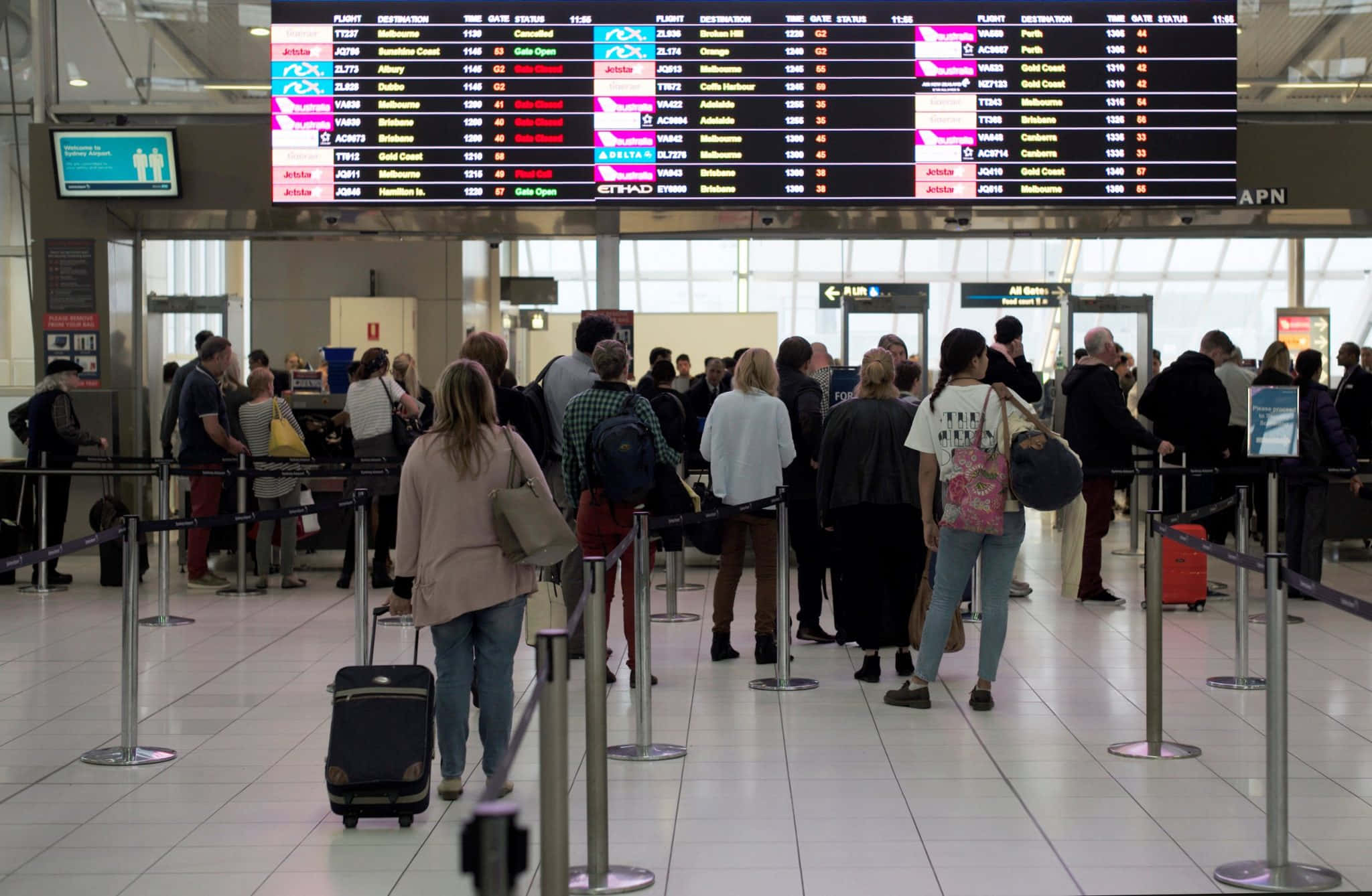 Airport 桌布 壁紙 — 乘客在機場航廈內，於發光的航班資訊板下排隊，顯示色彩繽紛的出發詳情。