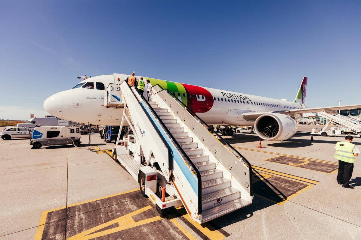 Airport 桌布 壁紙 — 乘客登上流動梯，走向停泊在晴朗機場停機坪上、藍天白雲下的TAP Portugal飛機。