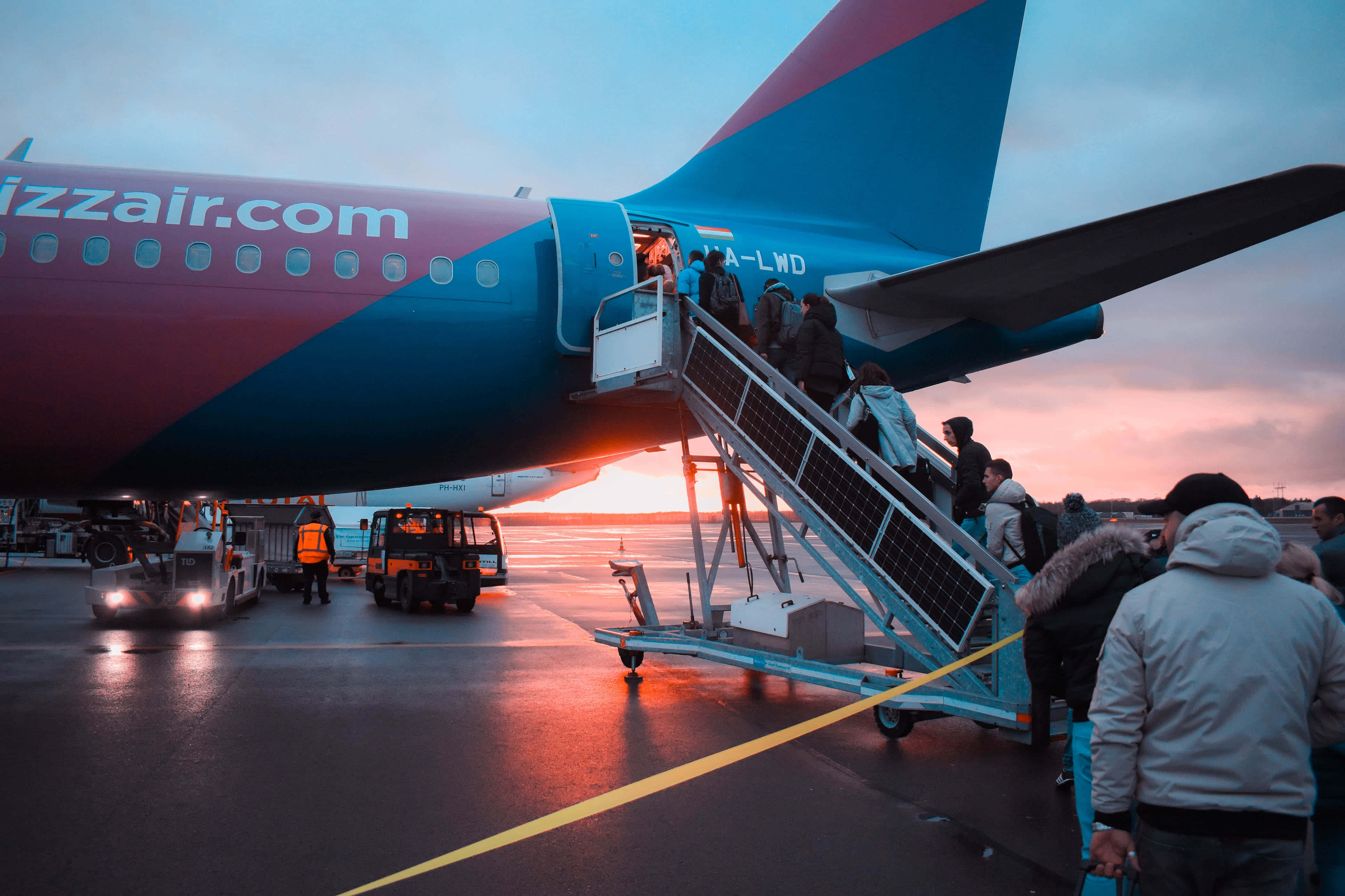 Airport 桌布 壁紙 — 乘客經由樓梯登上色彩繽紛的西南航空飛機，夕陽正落在濕漉漉的停機坪上。