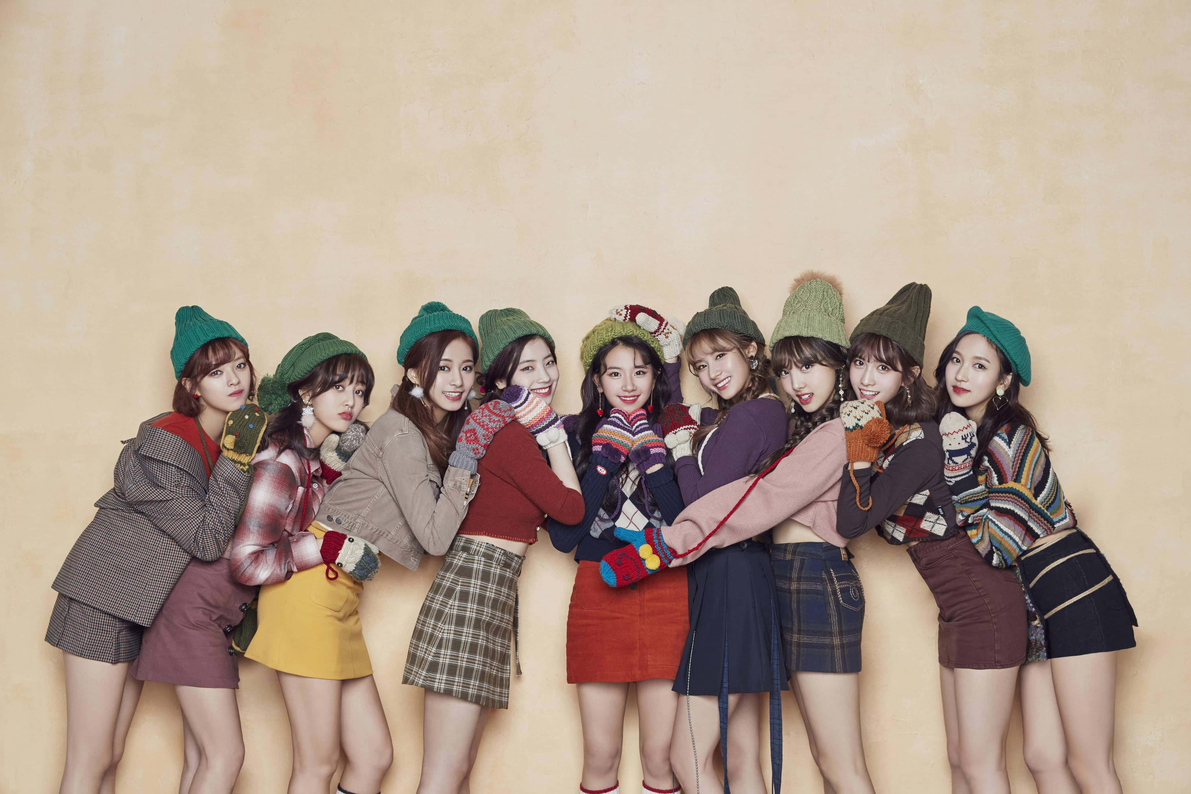 twice 桌布 壁紙 — 九位年輕女性戴著色彩繽紛的針織帽和舒適的冬季服裝，在溫暖的米色背景前緊密地擺姿勢。