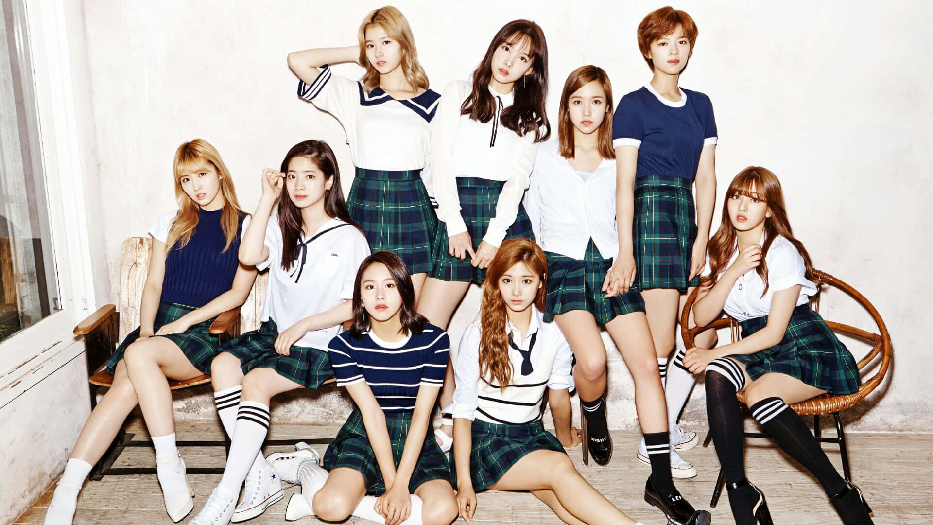 twice 桌布 壁紙 — 九位年輕女性穿著水手風格校服，在充滿陽光的房間裡自信地擺姿勢，房間裡有復古木椅。