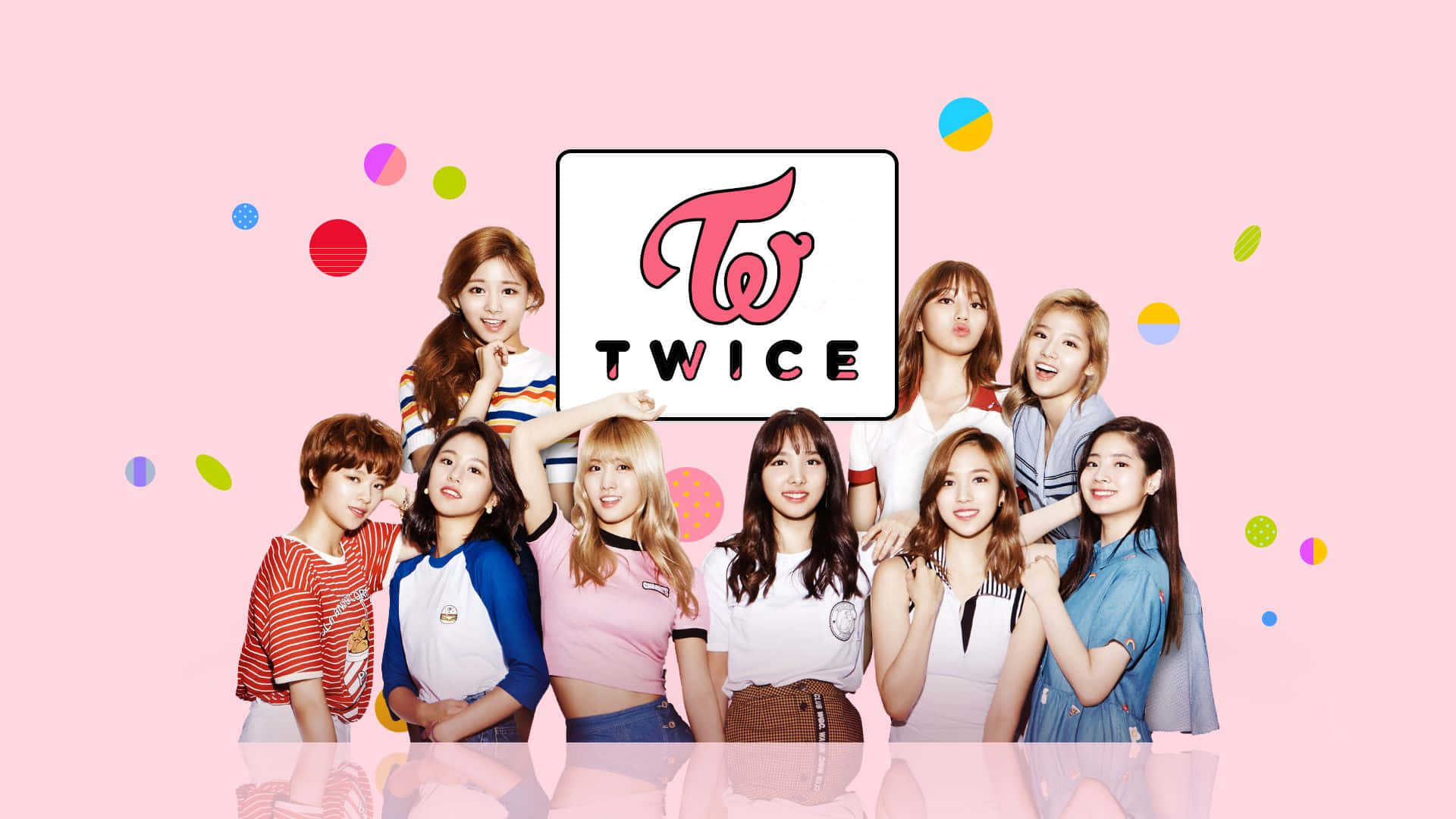 twice 桌布 壁紙 — 九位微笑的K-pop女孩在粉紅色柔和背景上，圍繞著她們的標誌，伴隨色彩繽紛的浮動圓圈，開心地擺姿勢。