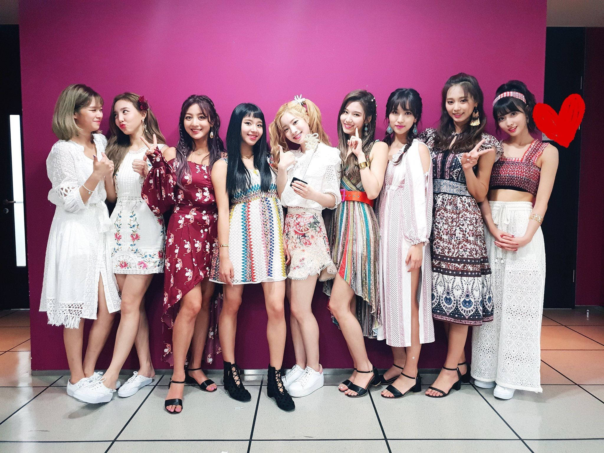 twice 桌布 壁紙 — 九位微笑的年輕女性穿著色彩繽紛的圖案服裝，在充滿活力的洋紅色牆前開心地擺姿勢。