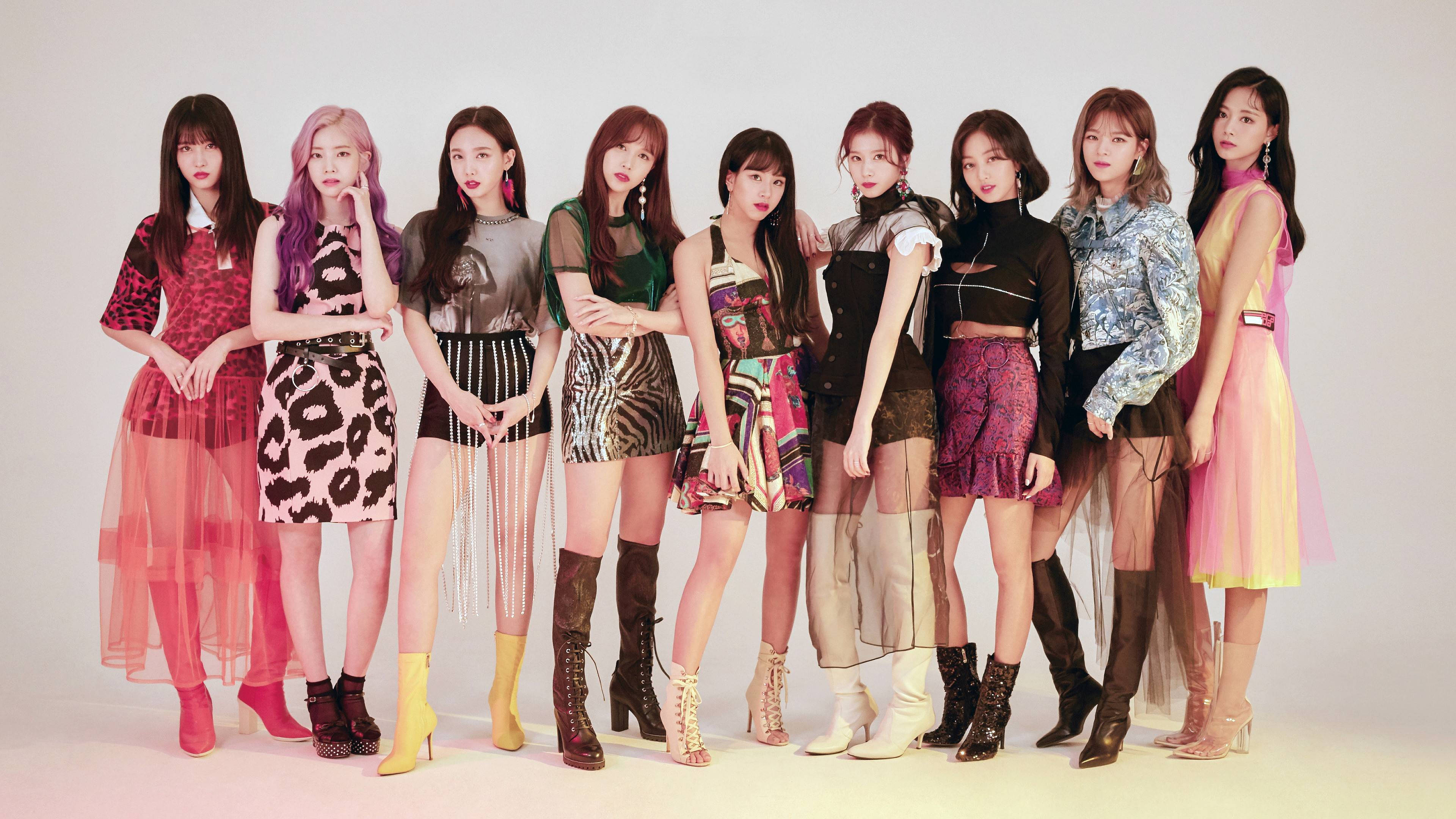 Kpop Aesthetic 桌布 壁紙 — 九位時尚女性穿著大膽圖案服裝，在純白色工作室背景前自信地擺姿勢。