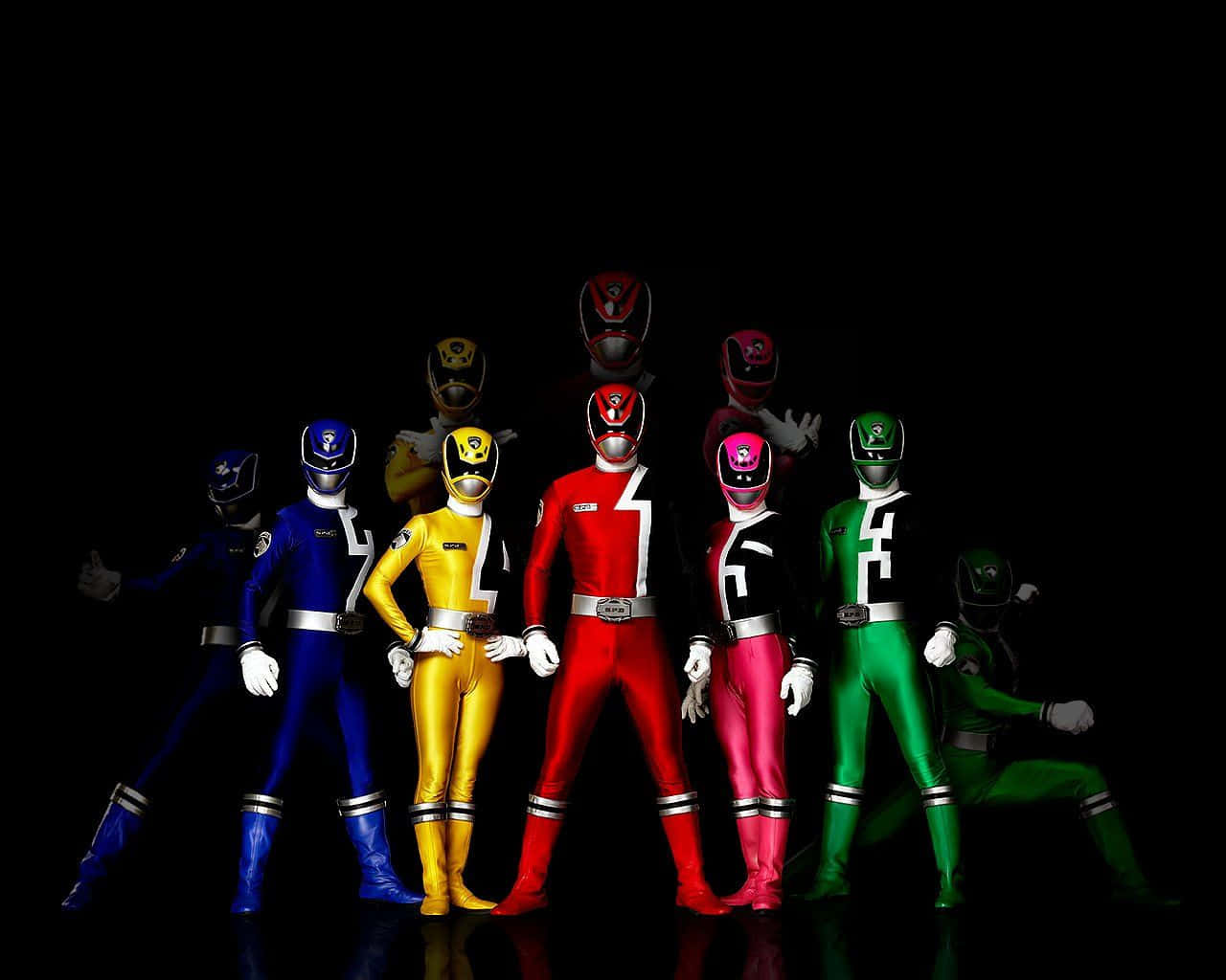 金剛戰士 桌布 壁紙 — 九位身穿色彩繽紛服裝的Power Rangers在黑色背景和戲劇性燈光下英勇站立。