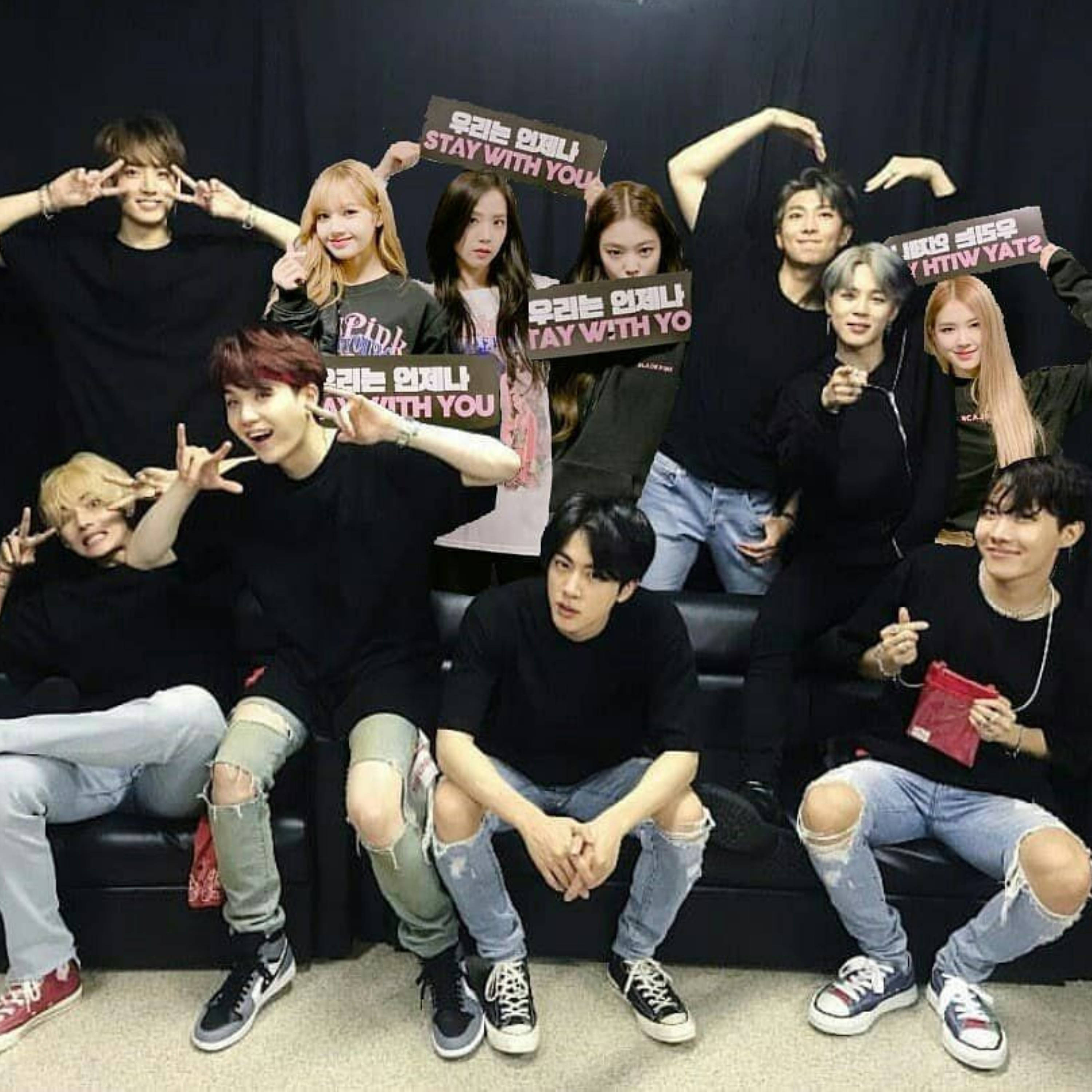 BTS 和 BLACKPINK 桌布 壁紙 — 九個年輕男子身穿黑色上衣和破洞牛仔褲，在黑色沙發上愉快地擺姿勢，手持寫有「STAY WITH YOU」的牌子，場景為攝影棚。