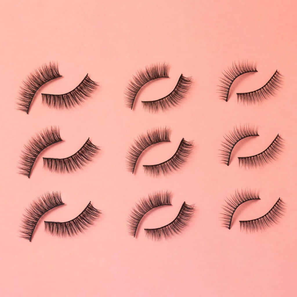 Eyelash 桌布 壁紙 — 九對黑色假睫毛在柔和的粉紅色背景上以網格排列。