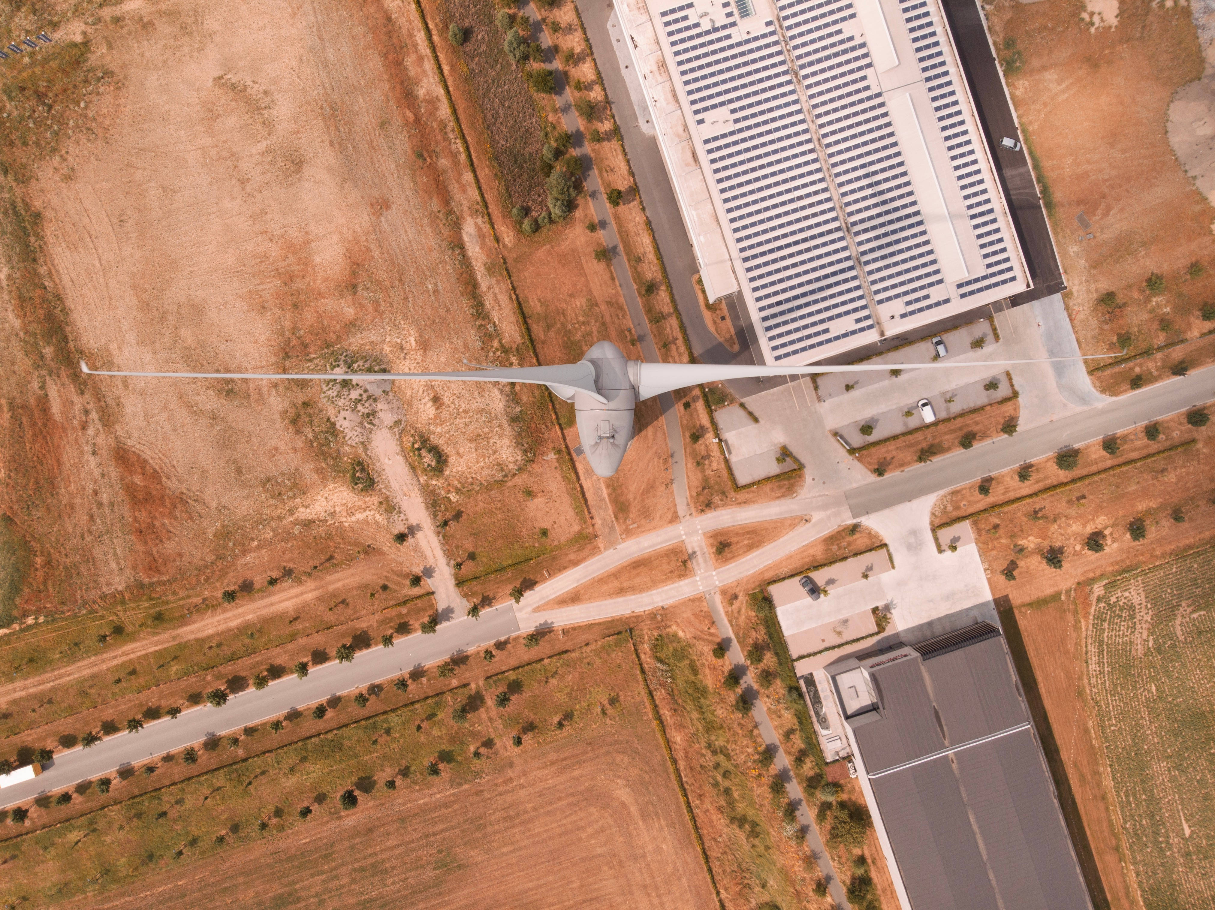 Energy 桌布 壁紙 — 乾旱土地上設有道路和建築物的風力渦輪機和太陽能電池板農場的鳥瞰圖。