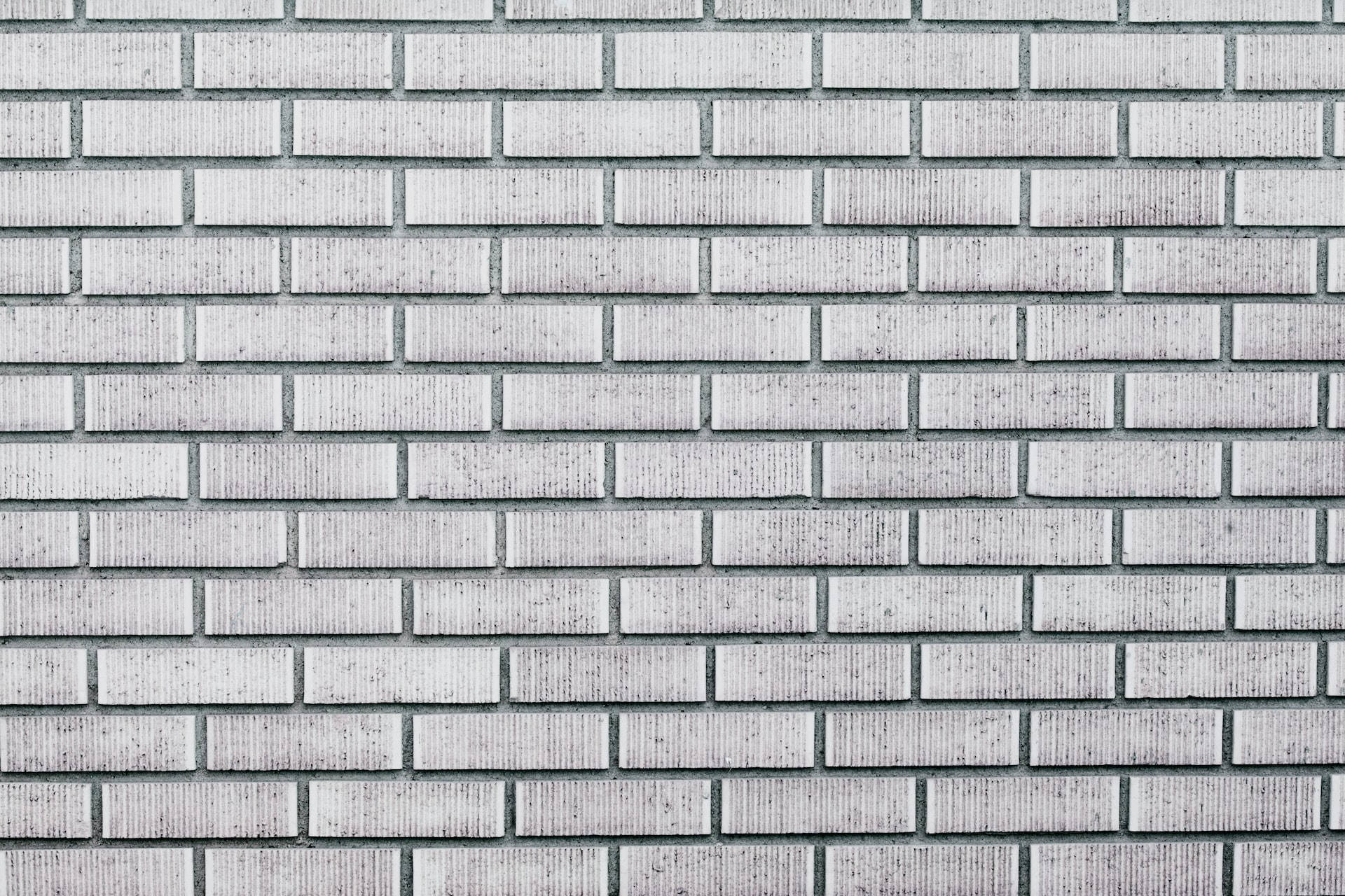 Brick Wall 桌布 壁紙 — 乾淨白色磚牆的特寫，帶有細微紋理和砂漿線條，在柔和日光下。