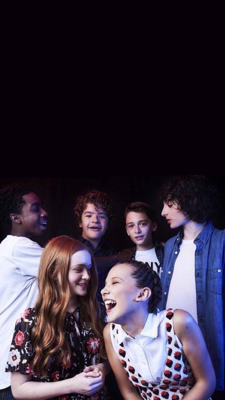 Cast 桌布 壁紙 — 五位年輕演員在昏暗的場景中分享歡樂的笑聲和俏皮的表情。