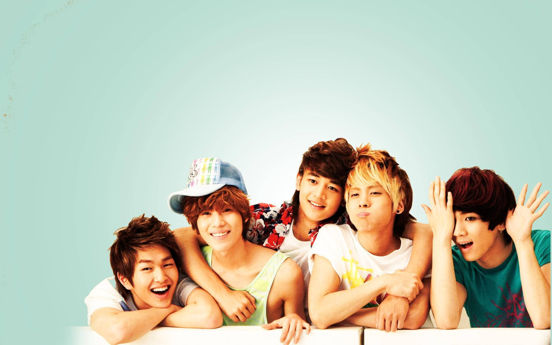 Shinee 桌布 壁紙 — 五位年輕男子，頭髮色彩繽紛，表情俏皮，靠在白色邊緣上，背景是柔和的青綠色。