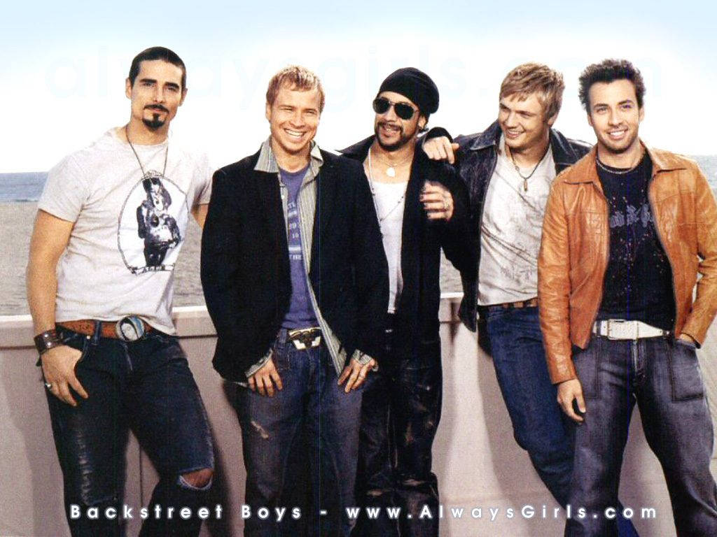 Backstreet 桌布 壁紙 — 五位微笑的 Backstreet Boys 在海邊陽台上休閒地擺姿勢，背景是明亮的藍天。